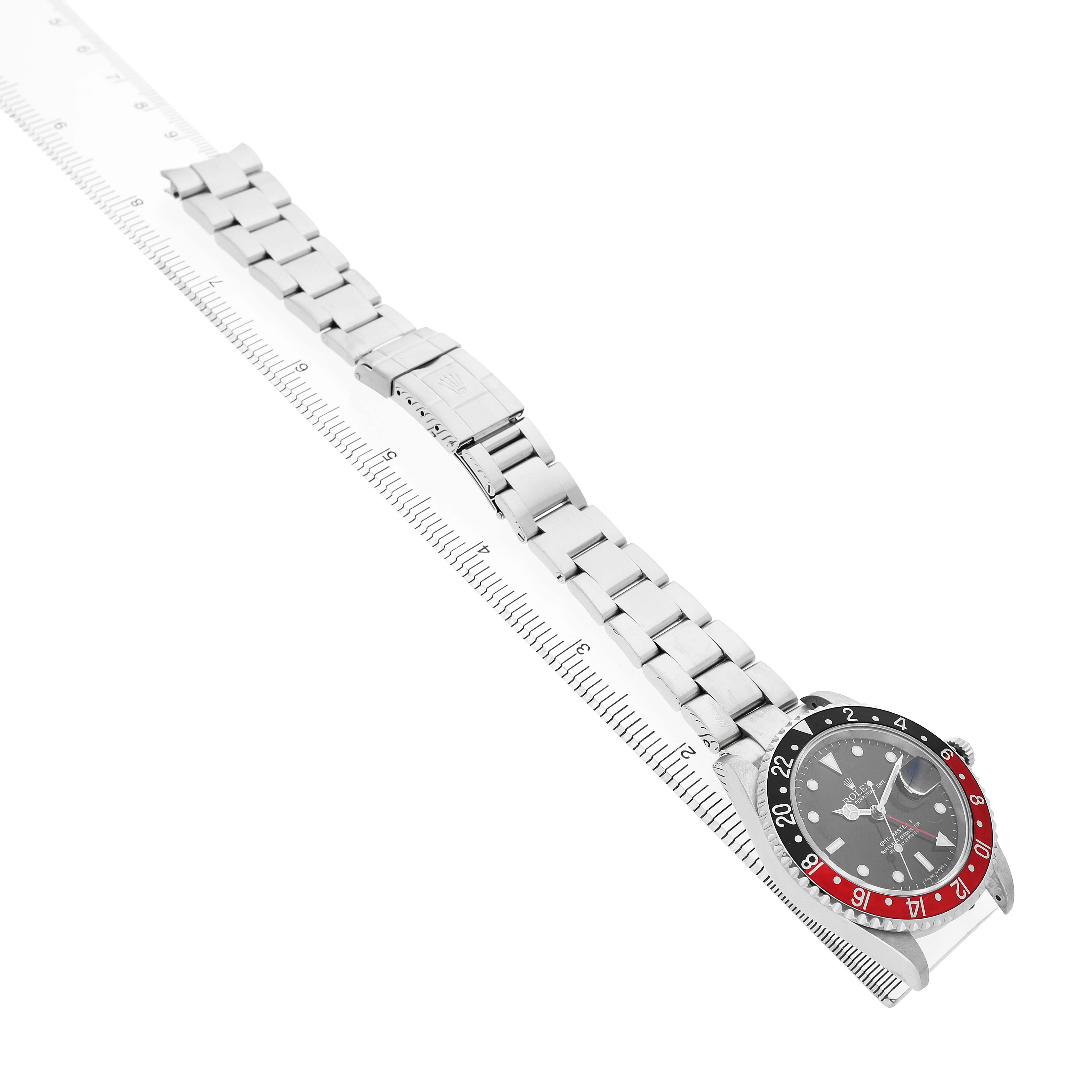 The Rolex GMT-Master 16710 Men's Stainless Steel Black Dial watch is shown at an angle displaying its face, bezel, and entire bracelet alongside a ruler for scale.