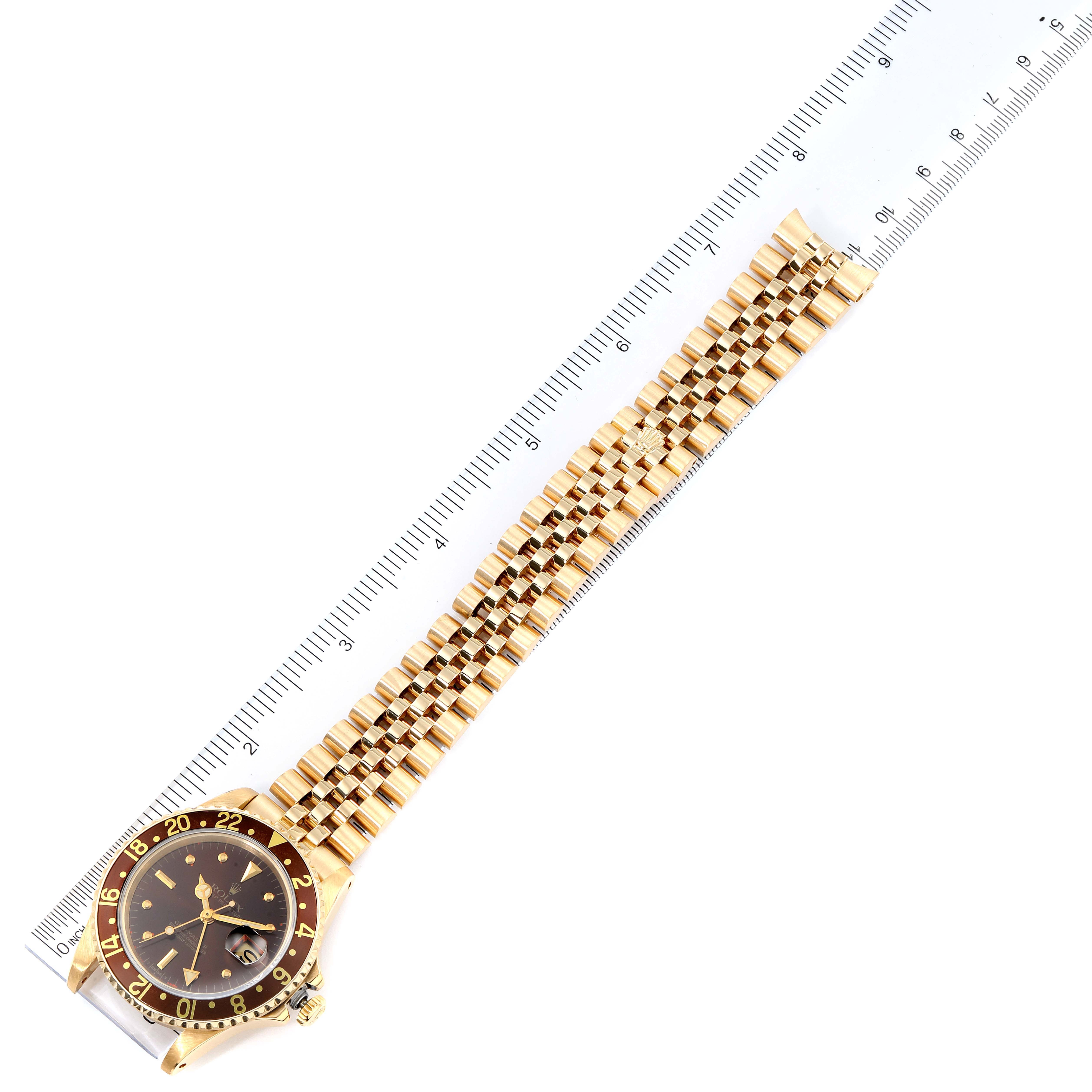 The image shows a Rolex GMT-Master 16758 Men's Yellow Gold Brown Dial 16758 Men's Yellow Gold Brown Dial watch with its brown and gold bezel and gold bracelet laid flat next to a ruler.