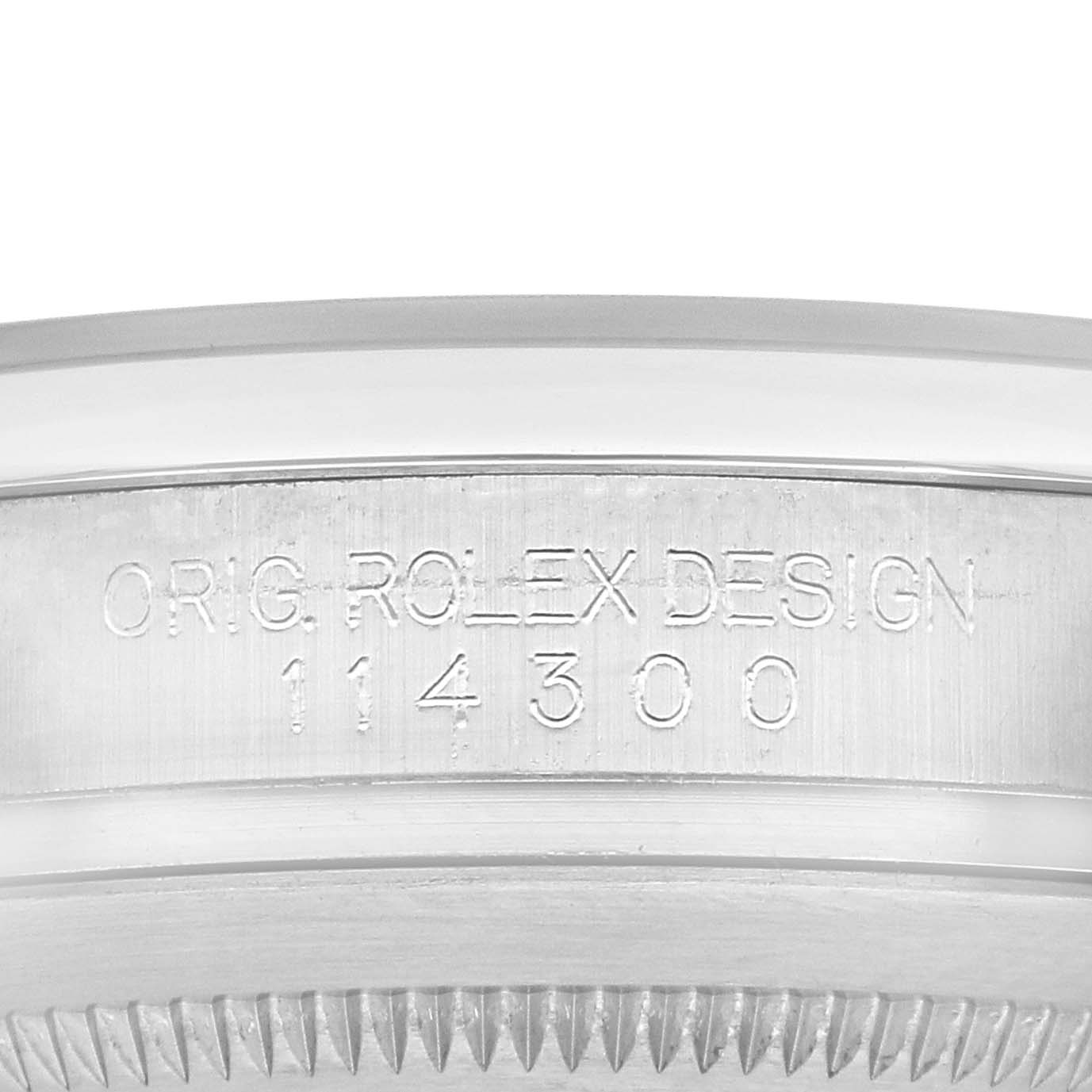 The image shows a close-up of the case side of a Rolex Oyster Perpetual 114300 Men's Stainless Steel Blue Dial 114300 Men's Stainless Steel Blue Dial, highlighting the model engraving.