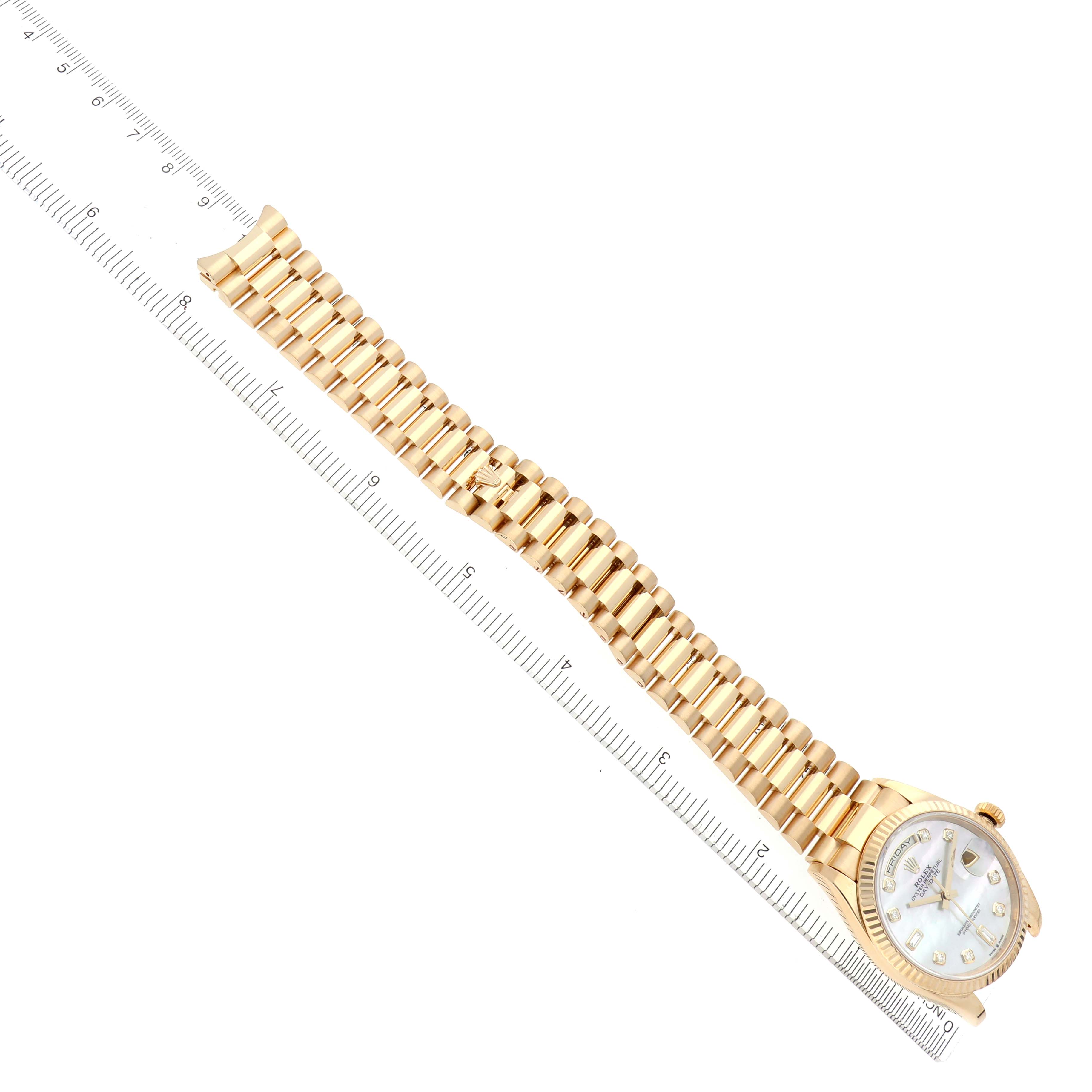The image shows a Rolex President 128238 Men's Yellow Gold Mother of Pearl Dial 128238 Men's Yellow Gold Mother of Pearl Dial watch angled diagonally, highlighting the gold bracelet and dial alongside a measuring ruler.