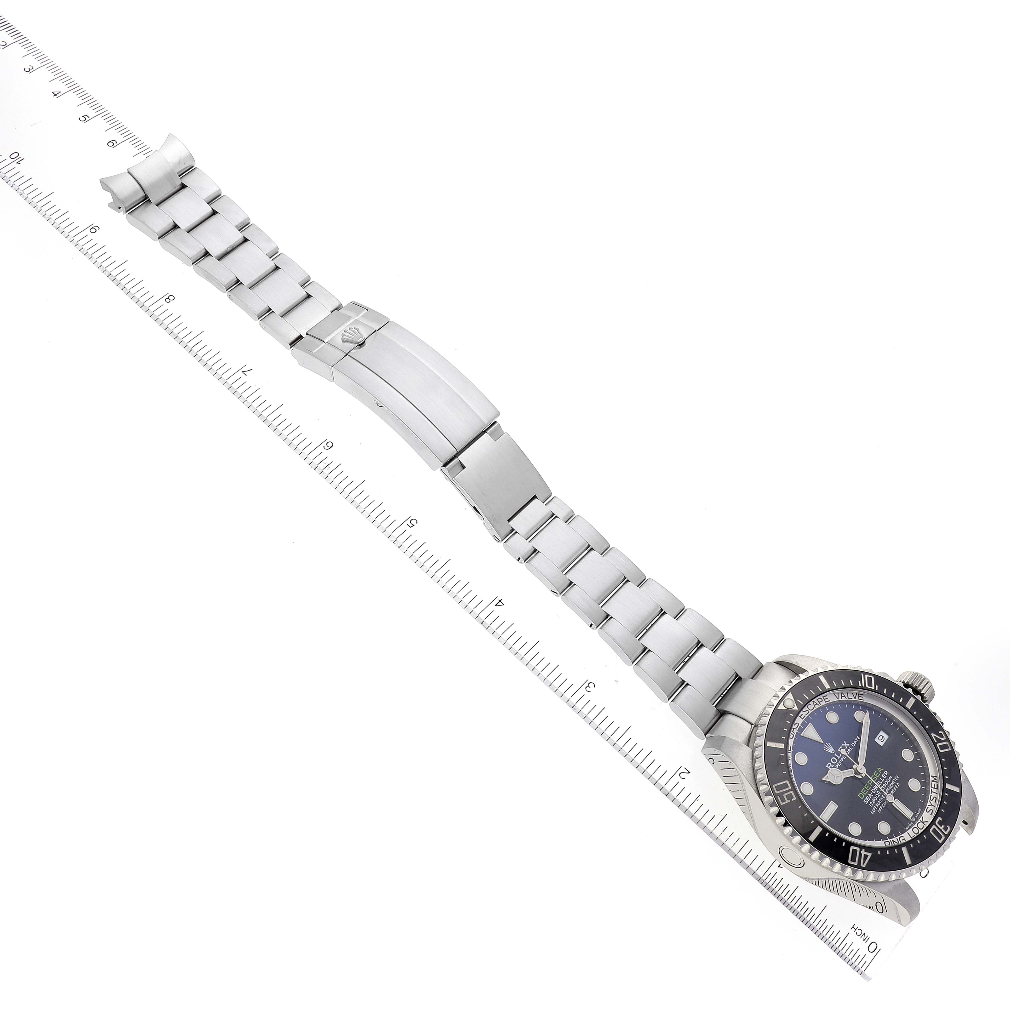The image shows a top-down view of a Rolex Sea-Dweller 126660 Men
s Stainless Steel Blue Dial 126660 Men
s Stainless Steel Blue Dial watch with its bracelet extended alongside a ruler.