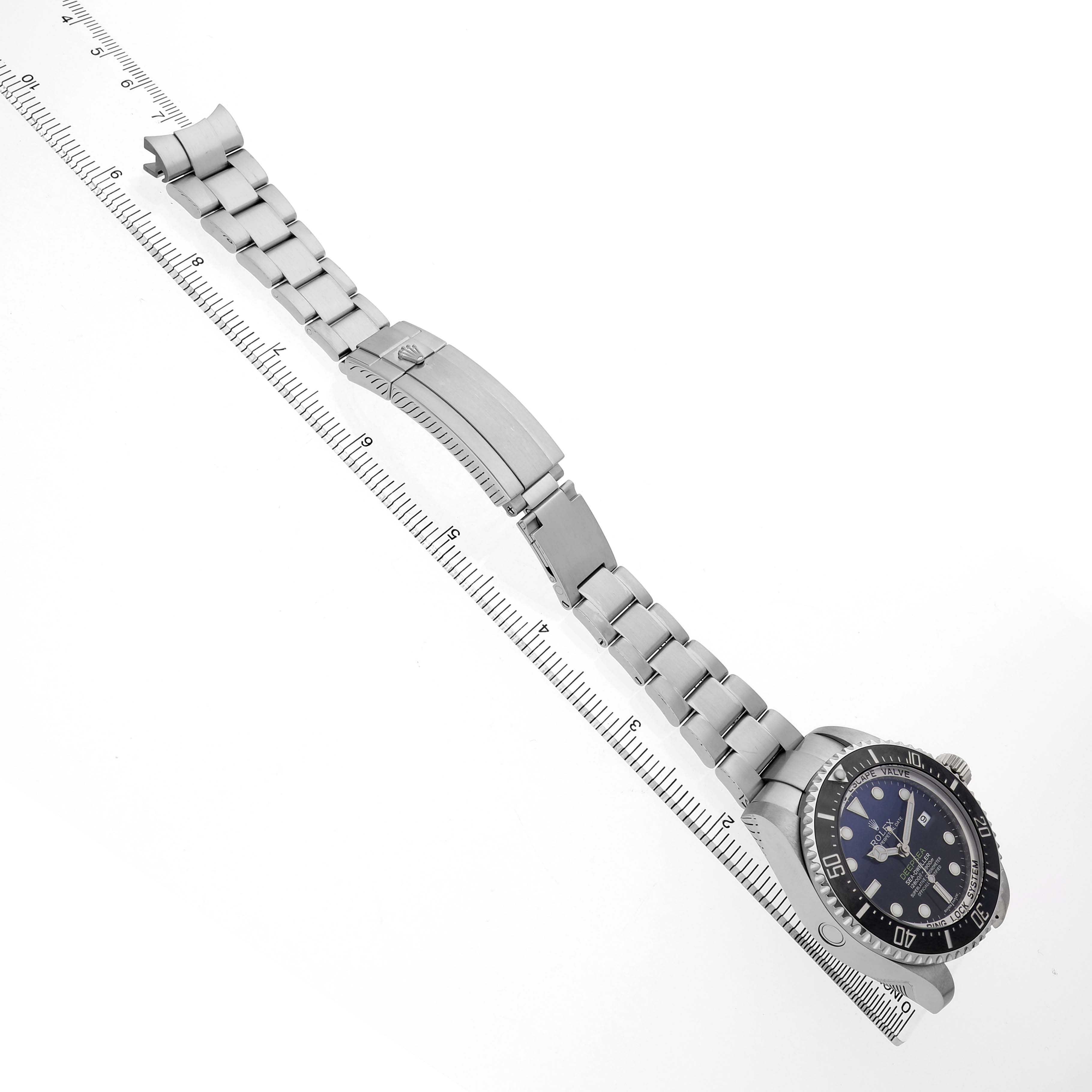 The Rolex Sea-Dweller 116660 Men's Stainless Steel Blue Dial watch is displayed at an angle, showcasing its face and full metal bracelet alongside a ruler for size reference.