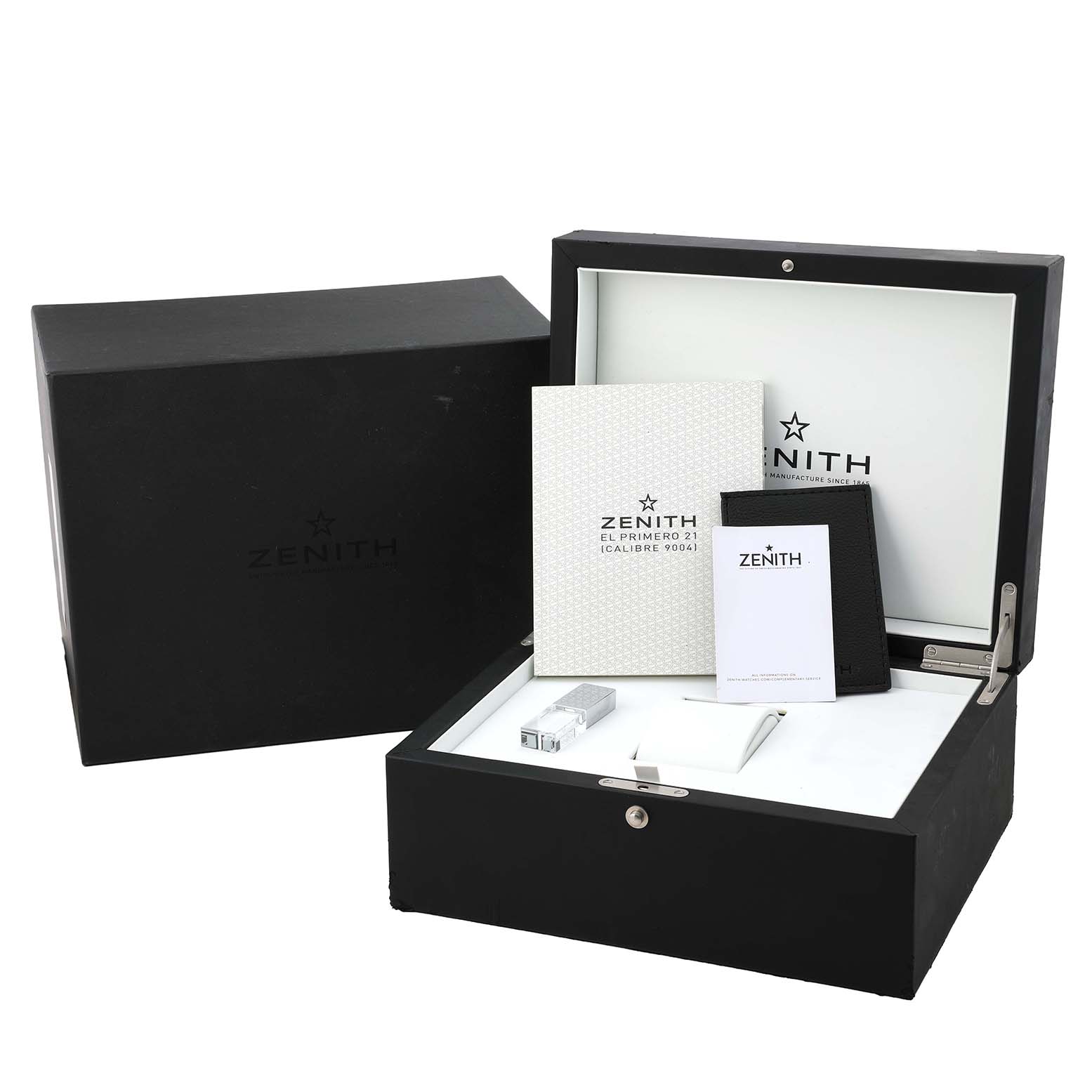 The image shows the Zenith Defy 49.9007.9004 Men's Ceramic Black Dial watch packaging, including a box, documentation, and accessories from a front angle.