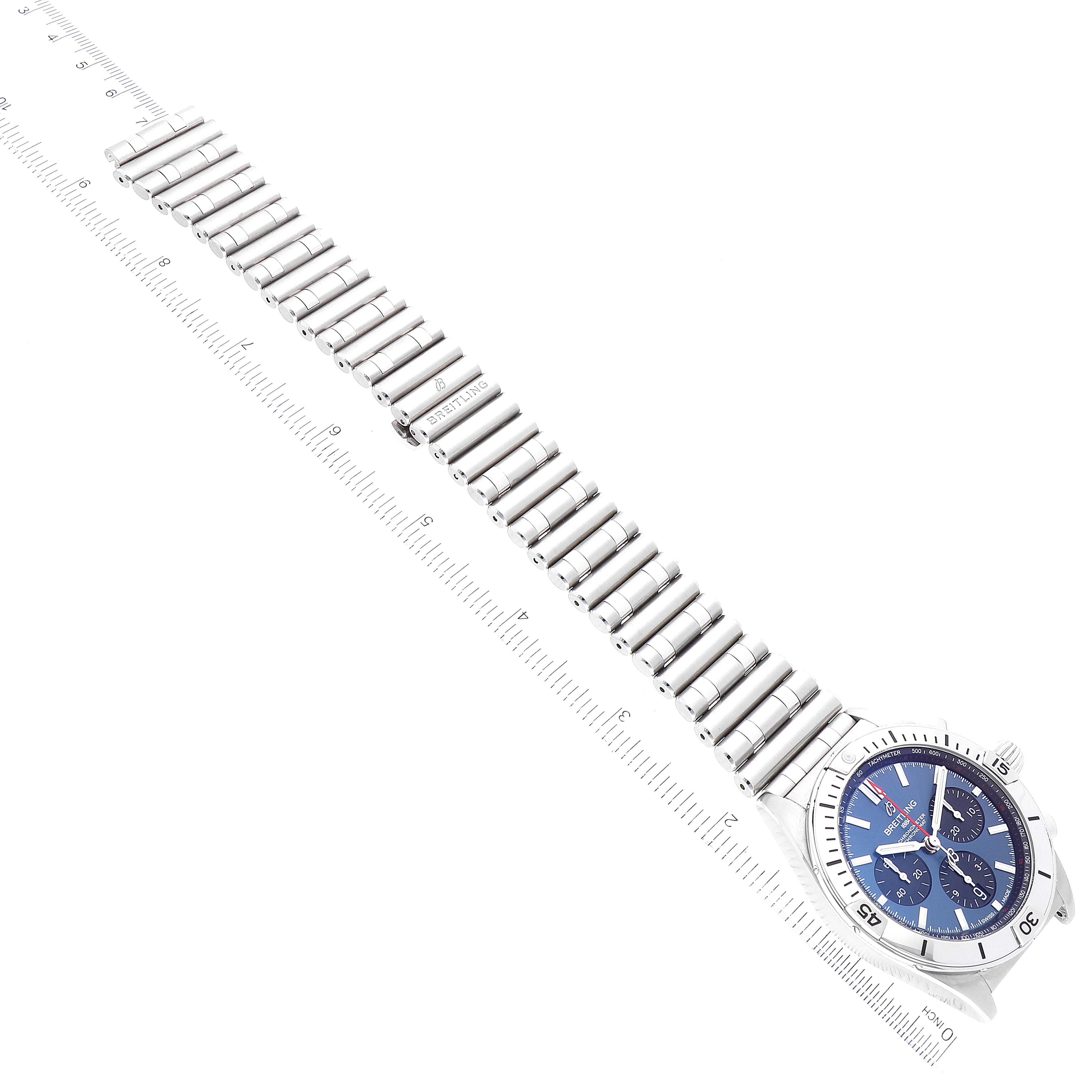 The Breitling Chronomat AB0134101C1A1 Men's Stainless Steel Blue Dial AB0134101C1A1 Men's Stainless Steel Blue Dial watch is shown from an elevated angle, displaying the face, bezel, and entire metal bracelet with rulers beside it.