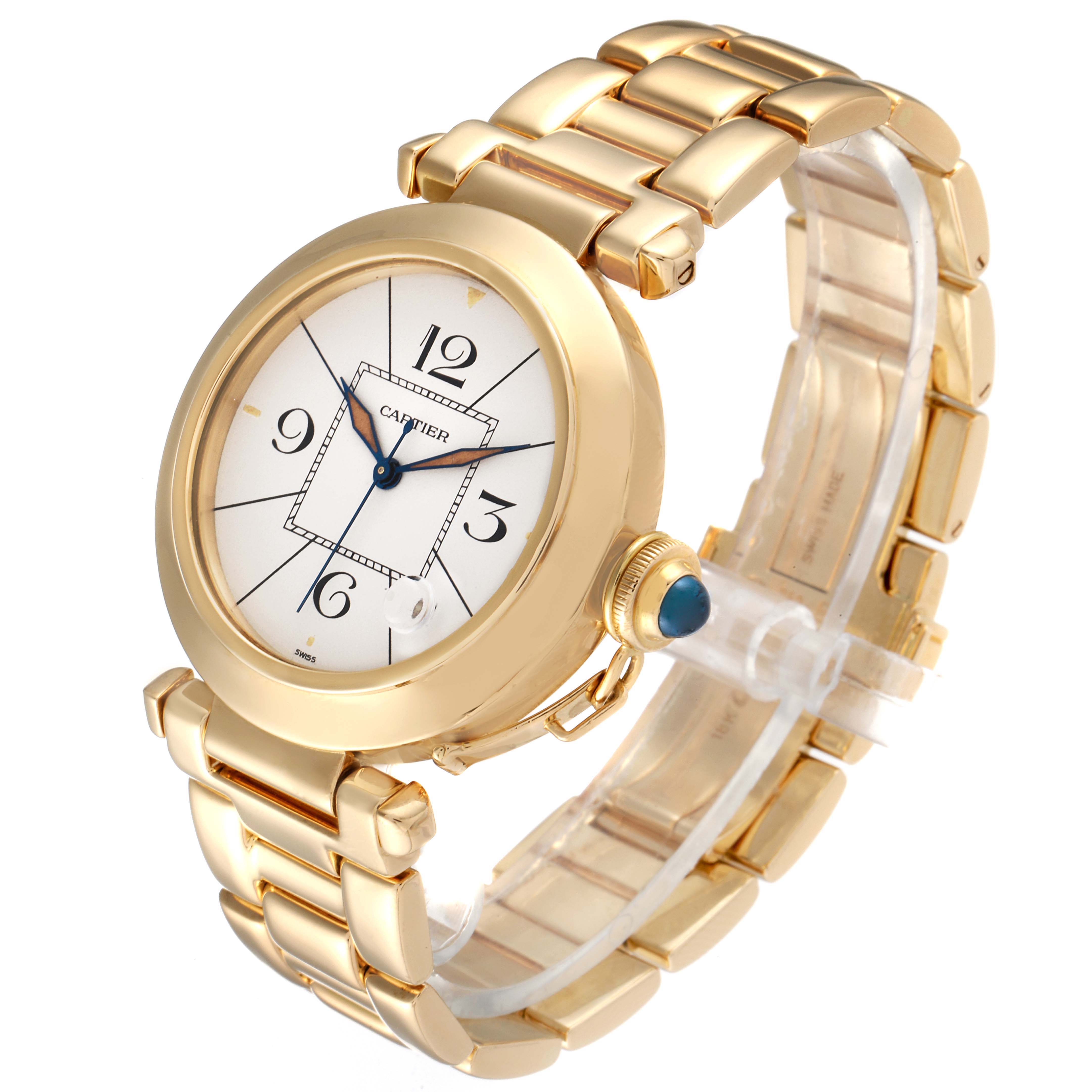 The Cartier Pasha 1989 Men's Yellow Gold Silver Dial 1989 Men's Yellow Gold Silver Dial watch is shown at an angled side view, displaying its gold bracelet, round face, and crown with a blue jewel.