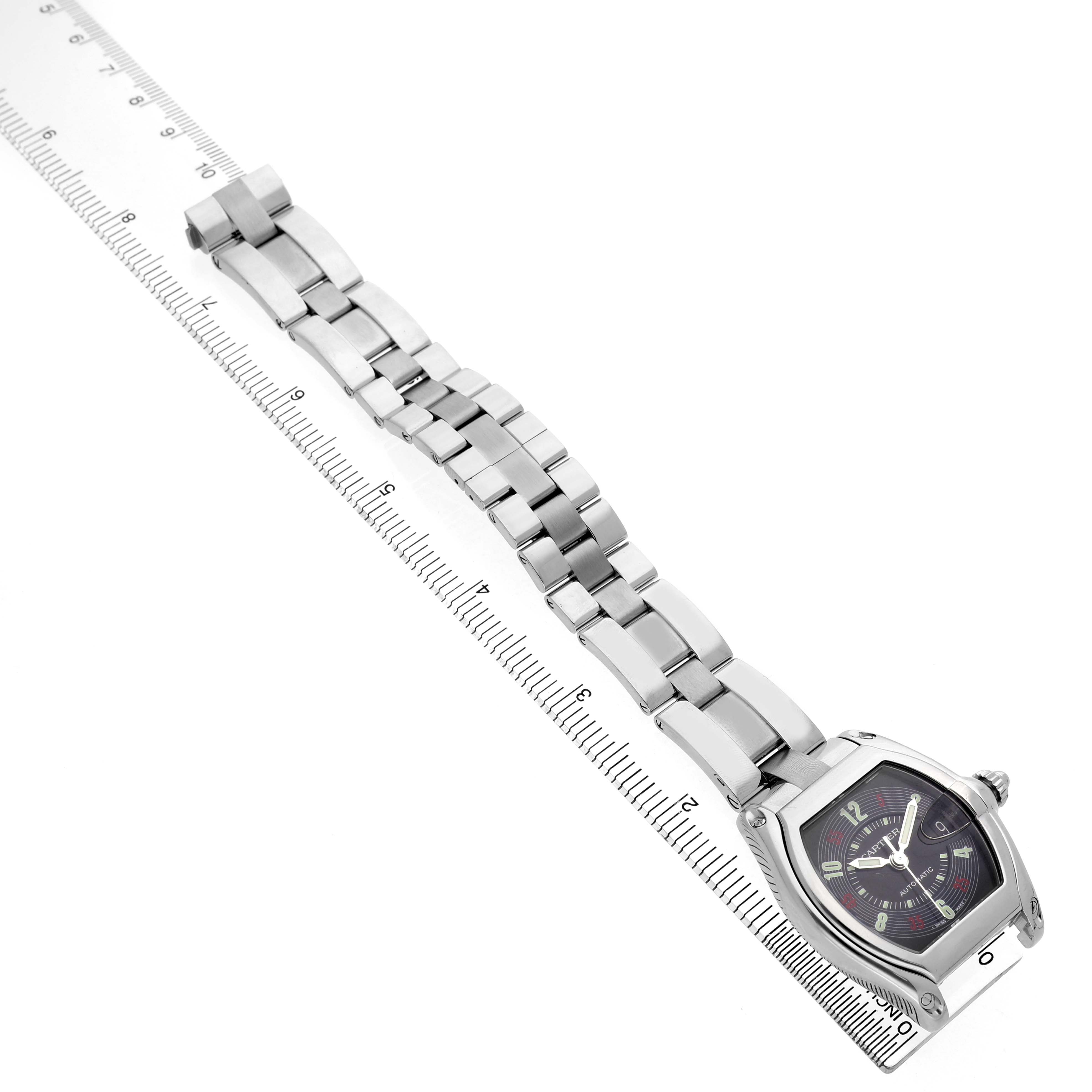 The Cartier Roadster W62002V3 Men's Stainless Steel Black Dial watch is shown from a front angle, with its face and metal bracelet aligned along a ruler.