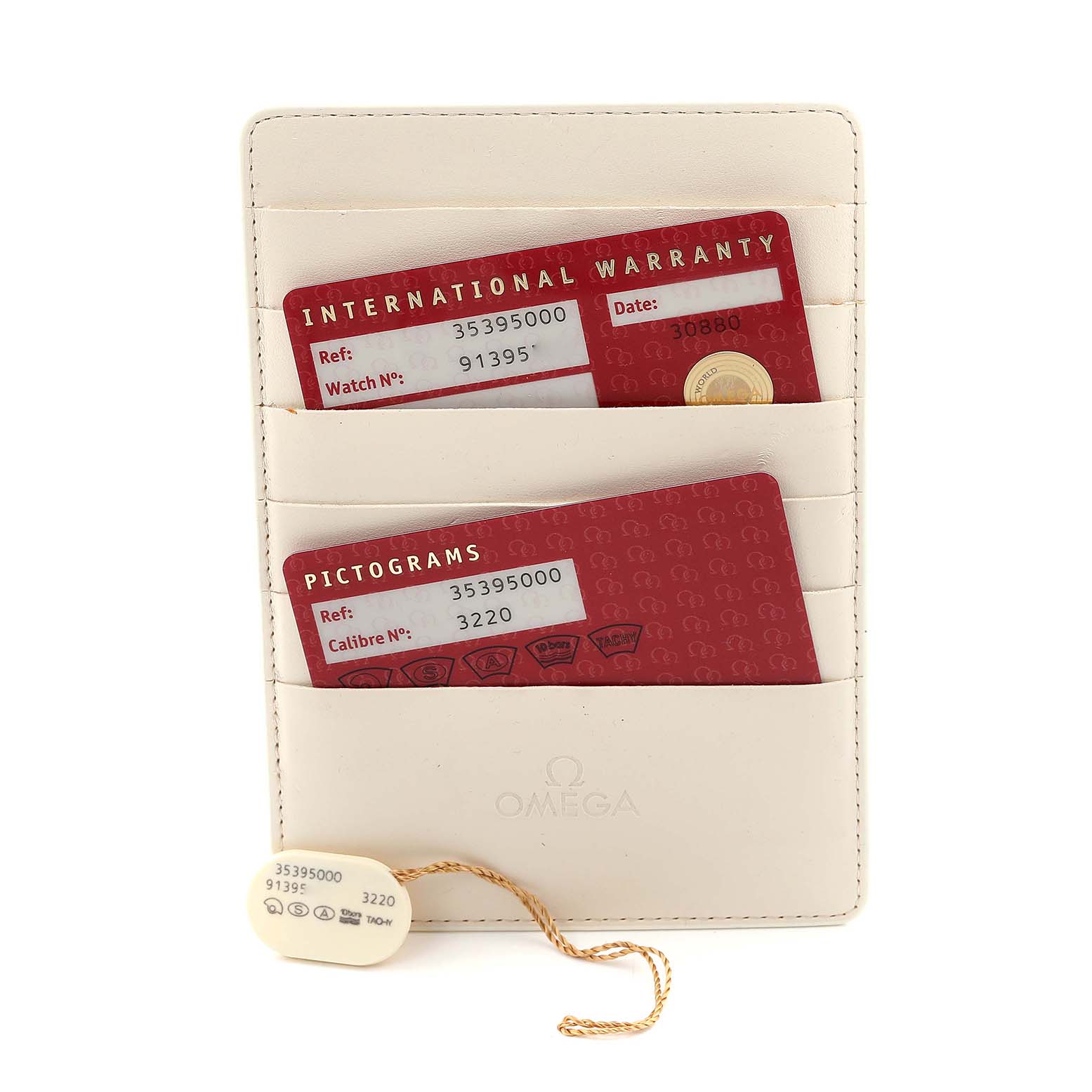 The image shows warranty and pictogram cards for an Omega Speedmaster 3539.50.00 Men
s Stainless Steel Black Dial 3539.50.00 Men
s Stainless Steel Black Dial, along with a tag, in a beige holder.