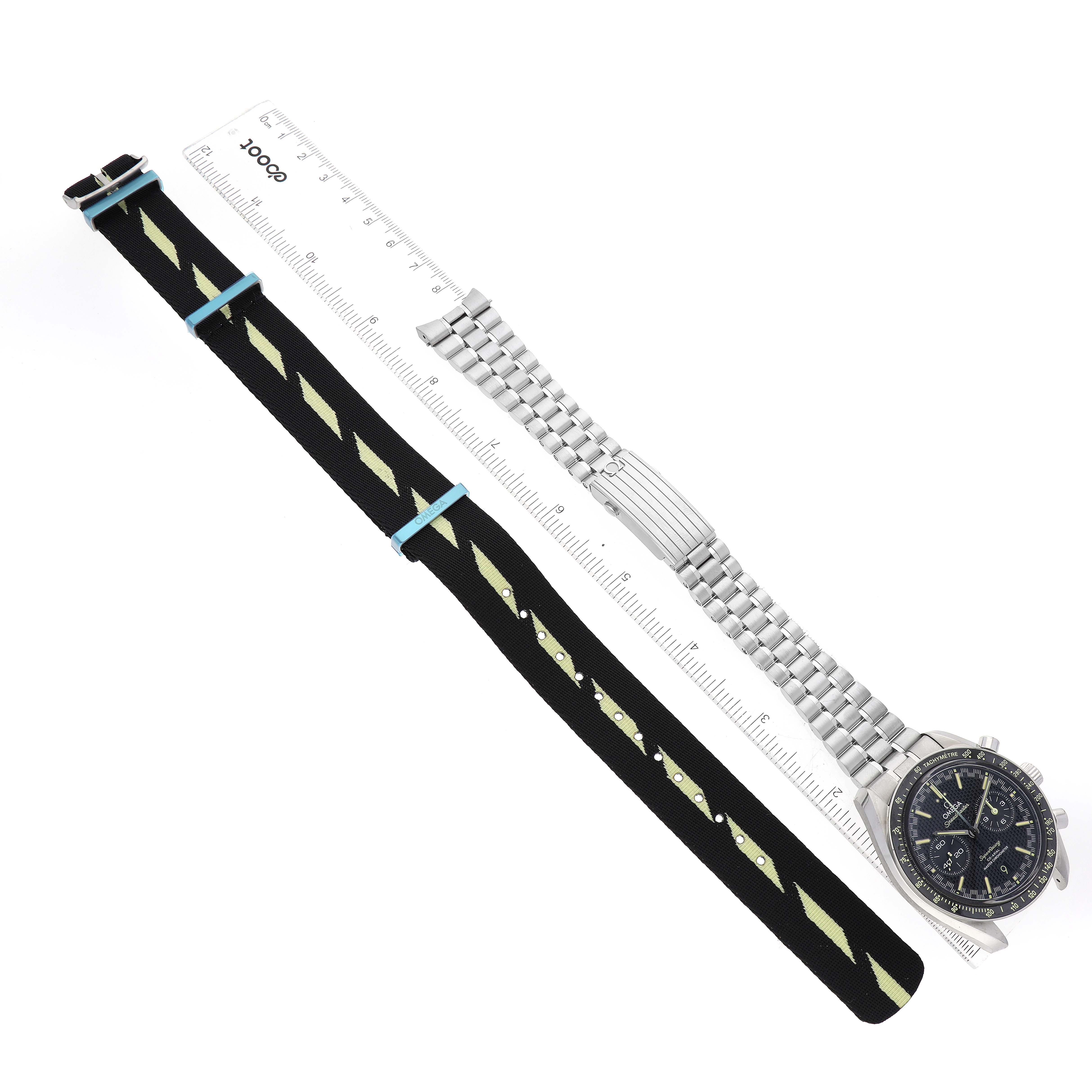 This image shows an Omega Speedmaster 329.30.44.51.01.003 Men's Stainless Steel Black Dial 329.30.44.51.01.003 Men's Stainless Steel Black Dial watch with a stainless steel bracelet, a fabric strap, and a measuring scale, all viewed from above.