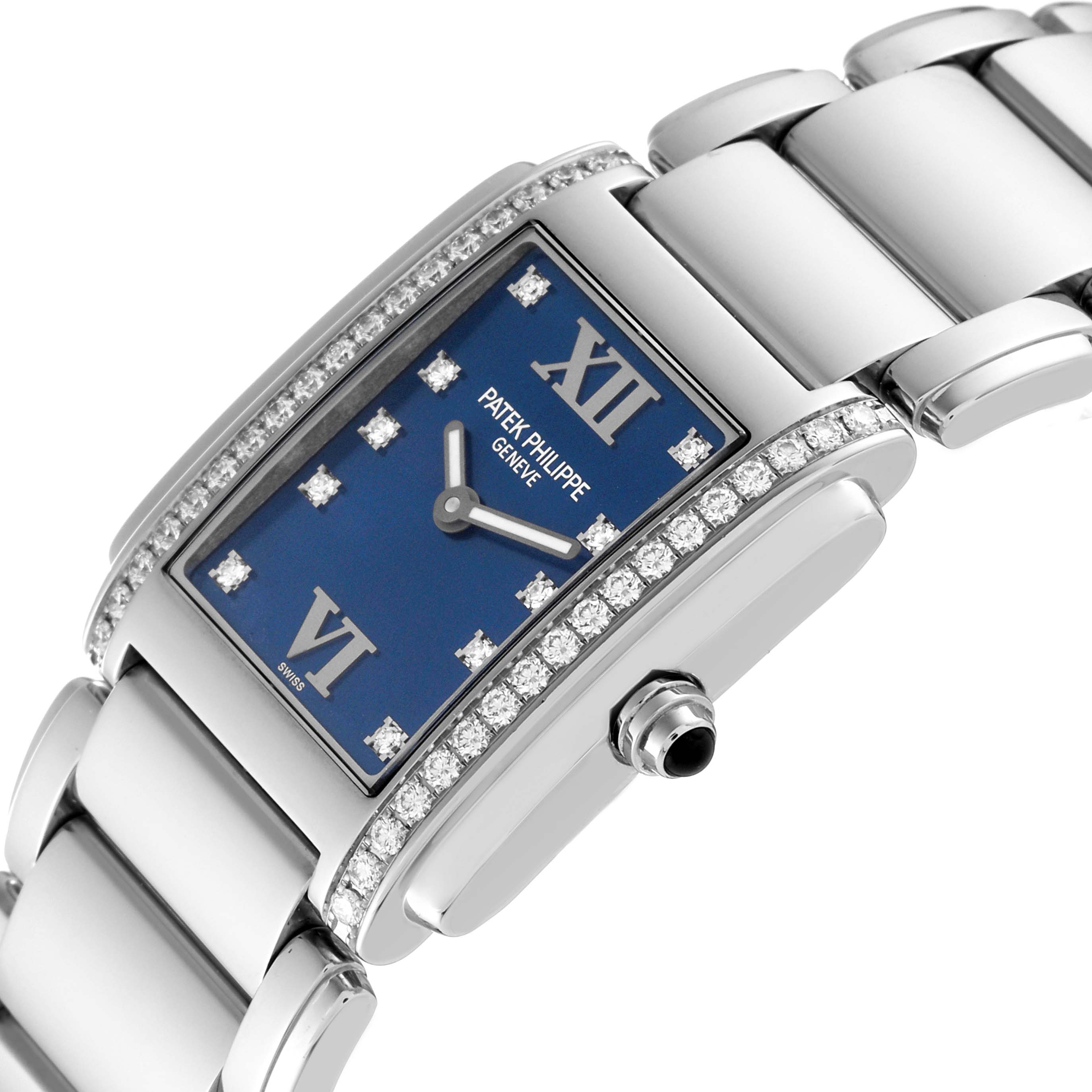 The image displays a tilted angle view of a Patek Philippe Twenty-4 4910/10A-012 Women's Stainless Steel Blue Dial 4910/10A-012 Women's Stainless Steel Blue Dial watch, highlighting the blue dial, diamond-set bezel, and metallic strap.