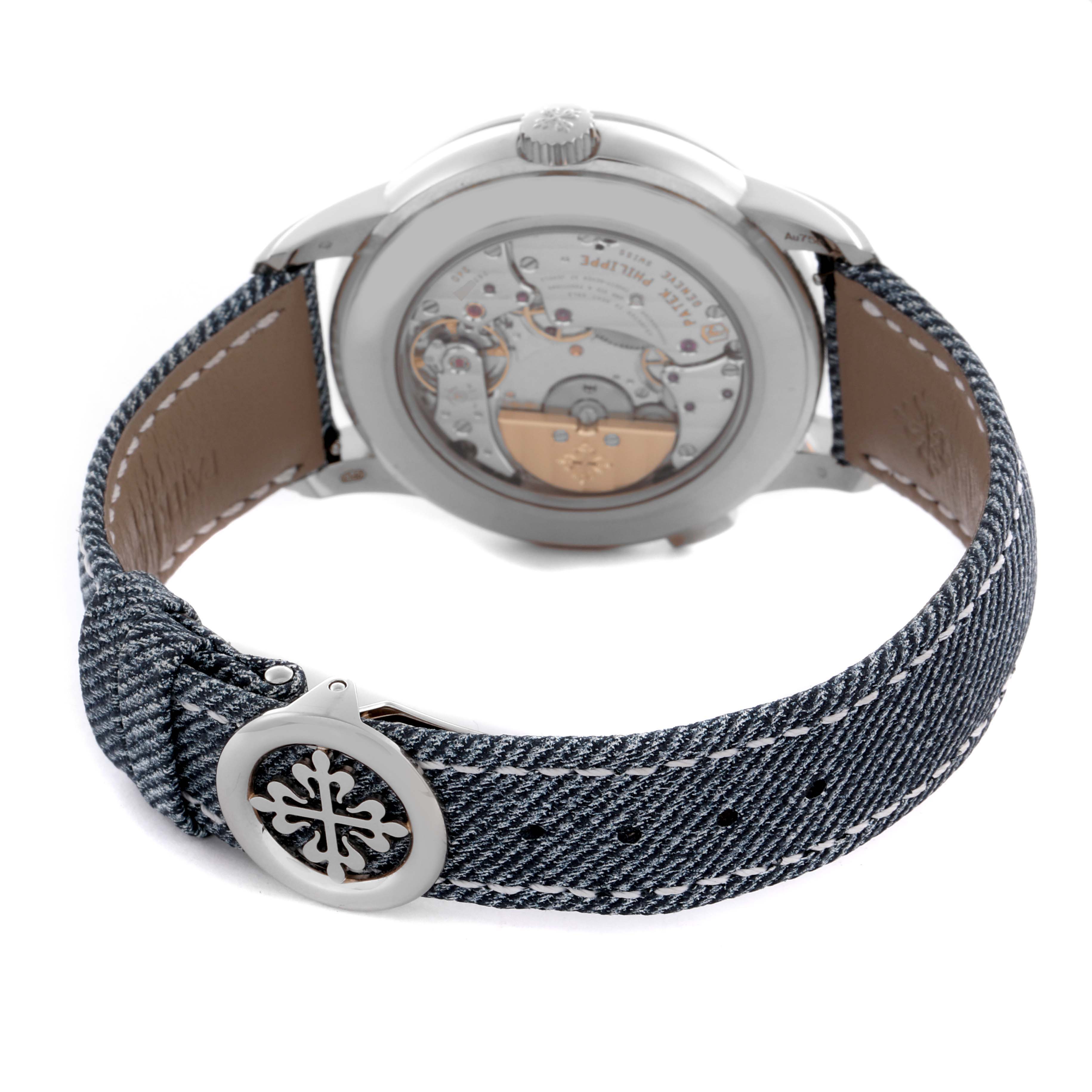 The Patek Philippe Complications 5330G-001 Men's White Gold Blue Dial 5330G-001 Men's White Gold Blue Dial watch is shown from the back, highlighting the movement and a denim-style strap with the brand's logo.