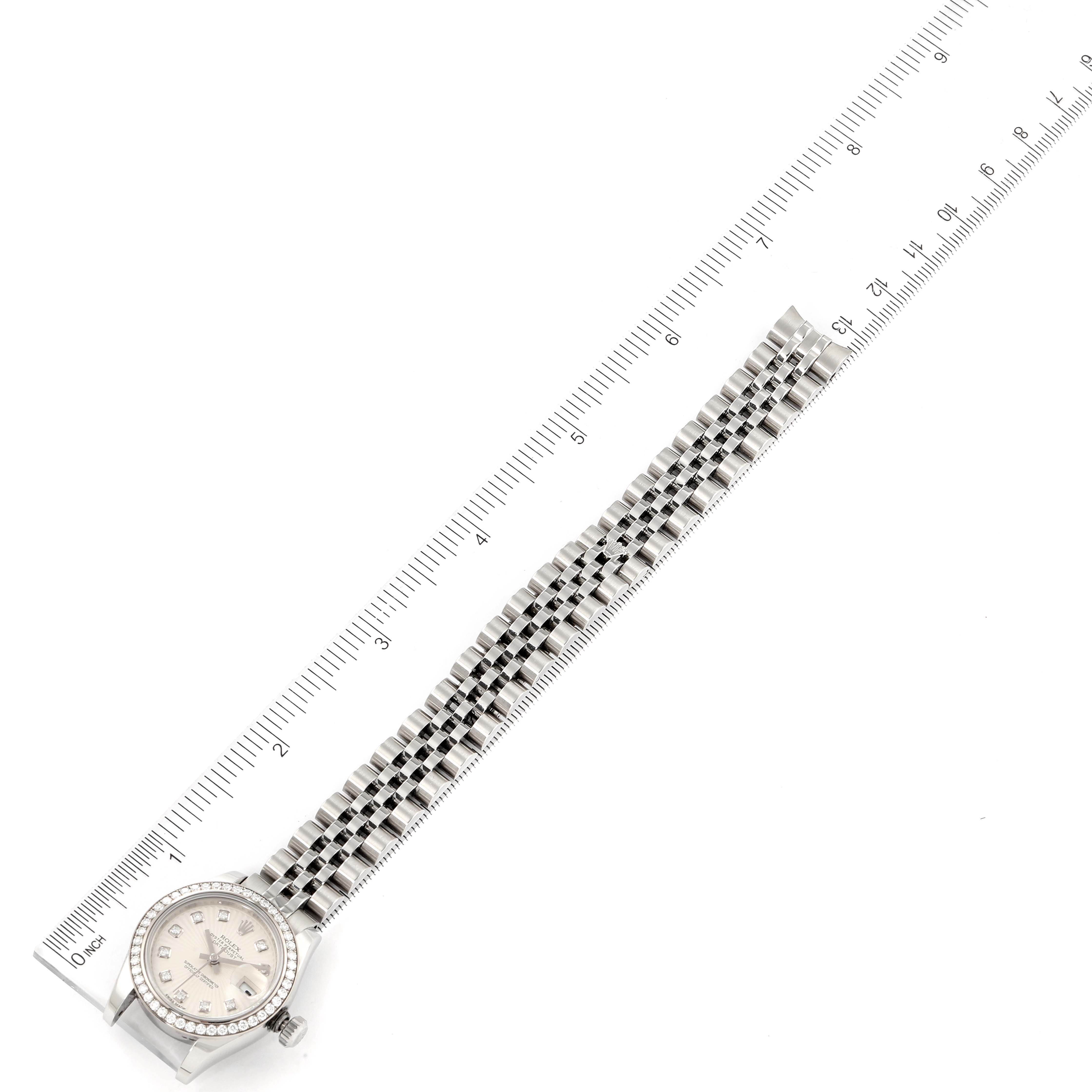 The image shows a Rolex Datejust 179384 Women's Stainless Steel Silver Dial 179384 Women's Stainless Steel Silver Dial watch from a top-down angle, displaying the face and full bracelet alongside a ruler.