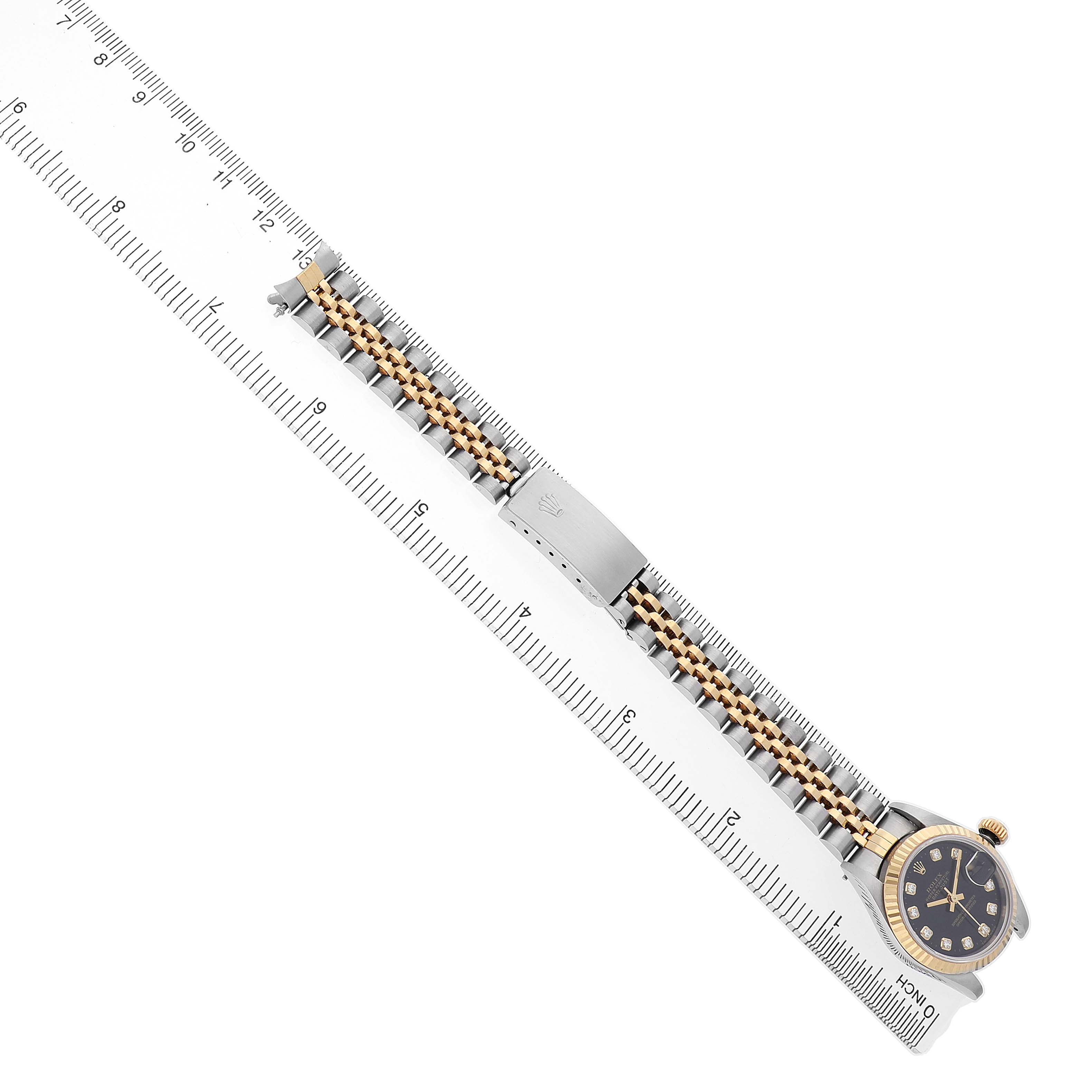 The Rolex Datejust 69173 Women's Steel and Gold (two tone) Black Dial watch is shown laid flat, featuring the case, bezel, bracelet, and clasp with a ruler for scale.