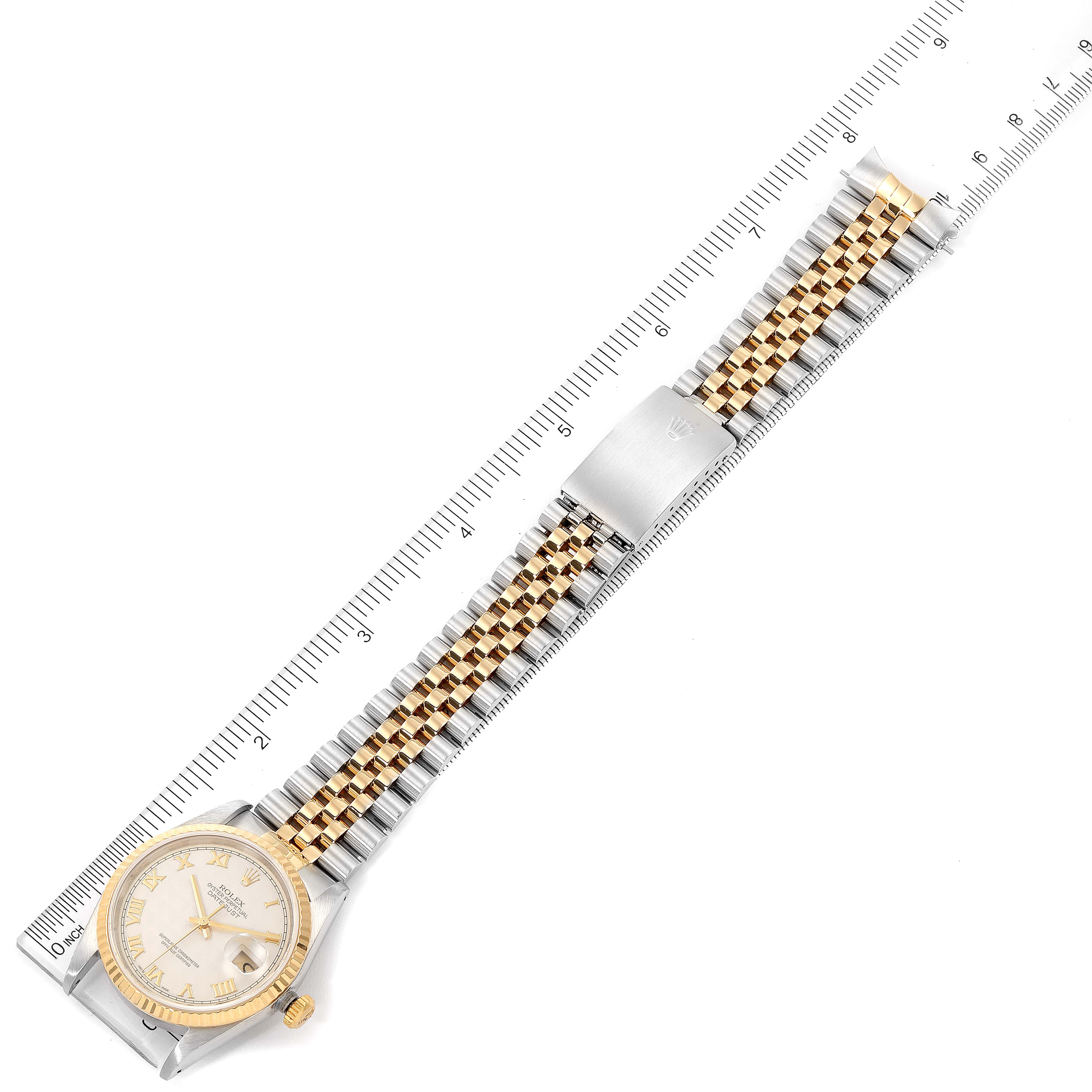 The Rolex Datejust 16233 Men
s Steel and Gold (two tone) Beige Dial 16233 Men
s Steel and Gold (two tone) Beige Dial watch is shown from the top view, displaying its face, two-tone bracelet, and clasp, laid beside a ruler.