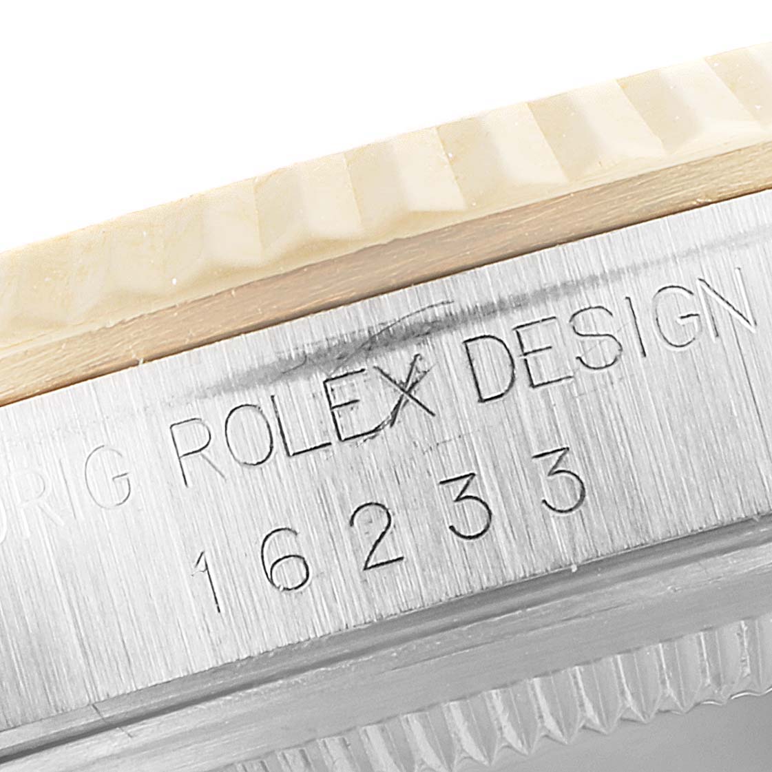 This close-up image shows the engraved model number of a Rolex Datejust 16233 Men
s Steel and Gold (two tone) Beige Dial 16233 Men
s Steel and Gold (two tone) Beige Dial 16233 on the watch case along with the fluted bezel.