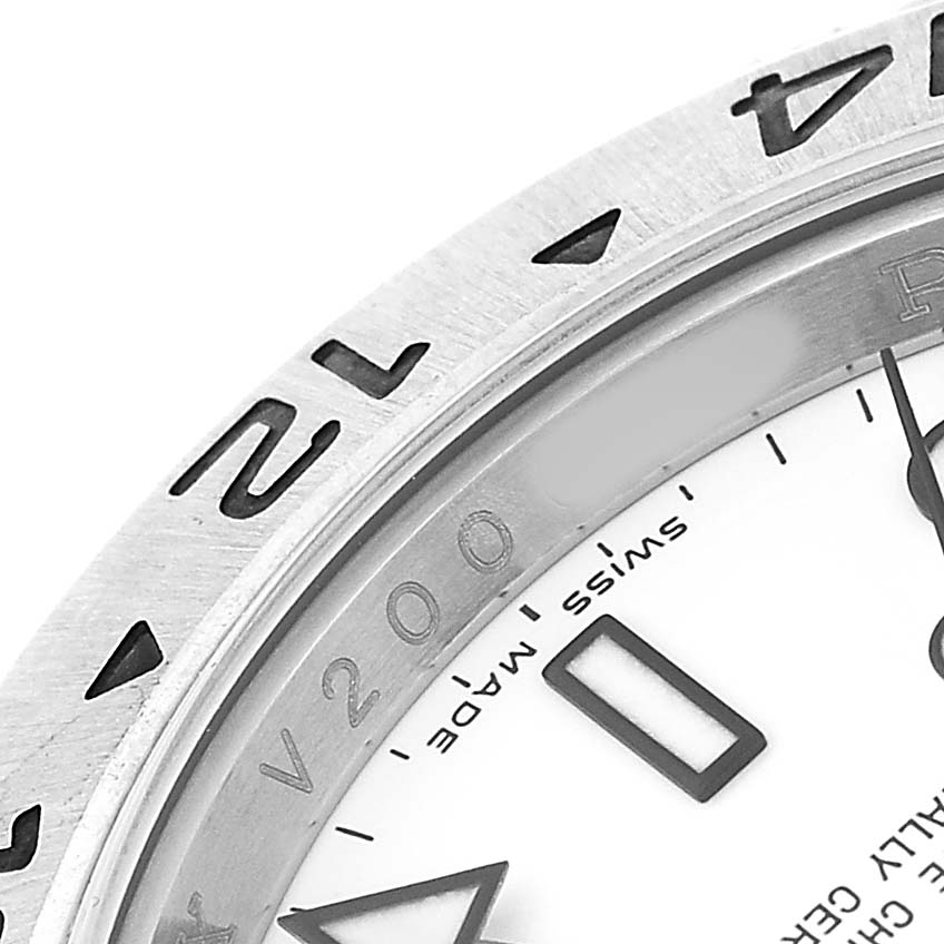 The image shows a close-up of the bezel and part of the dial of a Rolex Explorer 16570 Men's Stainless Steel White Dial watch, highlighting the 12 o'clock marker and text.