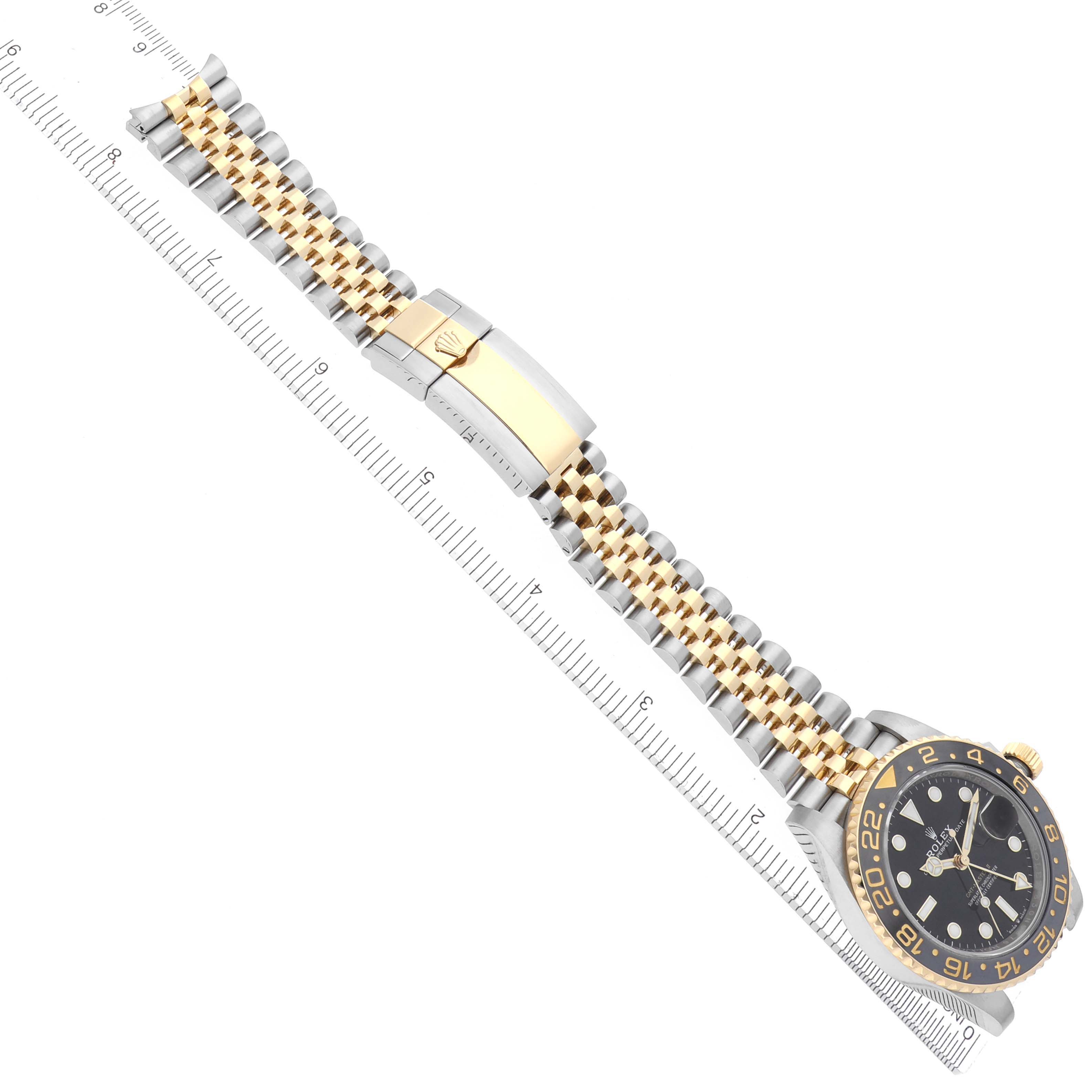 The Rolex GMT-Master 126713GRNR Men's Steel and Gold (two tone) Black Dial 126713GRNR Men's Steel and Gold (two tone) Black Dial watch is shown from an angled top view, displaying the dial, bezel, and full bracelet with a ruler alongside it.