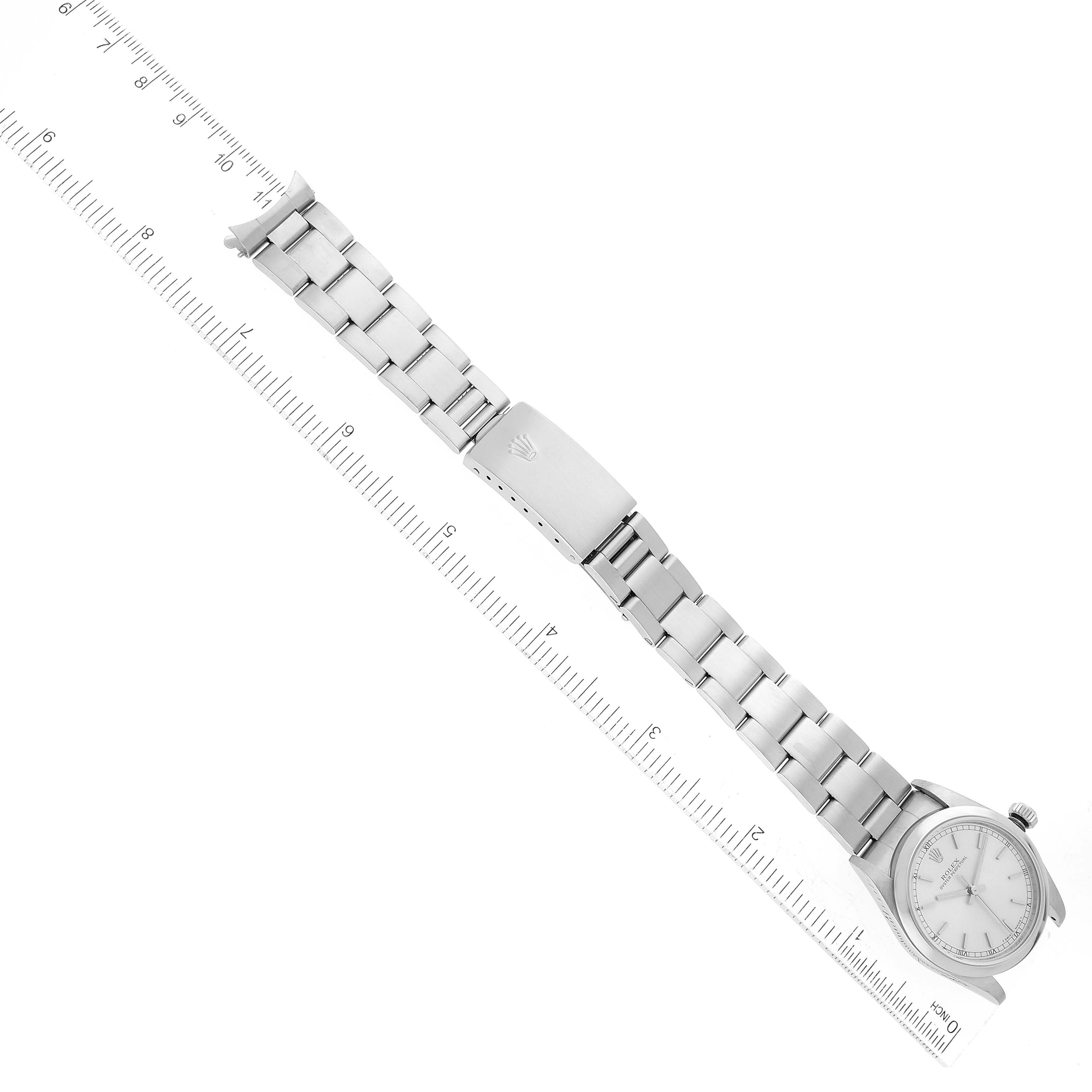 The image shows a flat lay of the Rolex Mid-Size 77080 Women
s Stainless Steel Silver Dial 77080 Women
s Stainless Steel Silver Dial watch, displaying its full bracelet, clasp, and face with a ruler for scale.