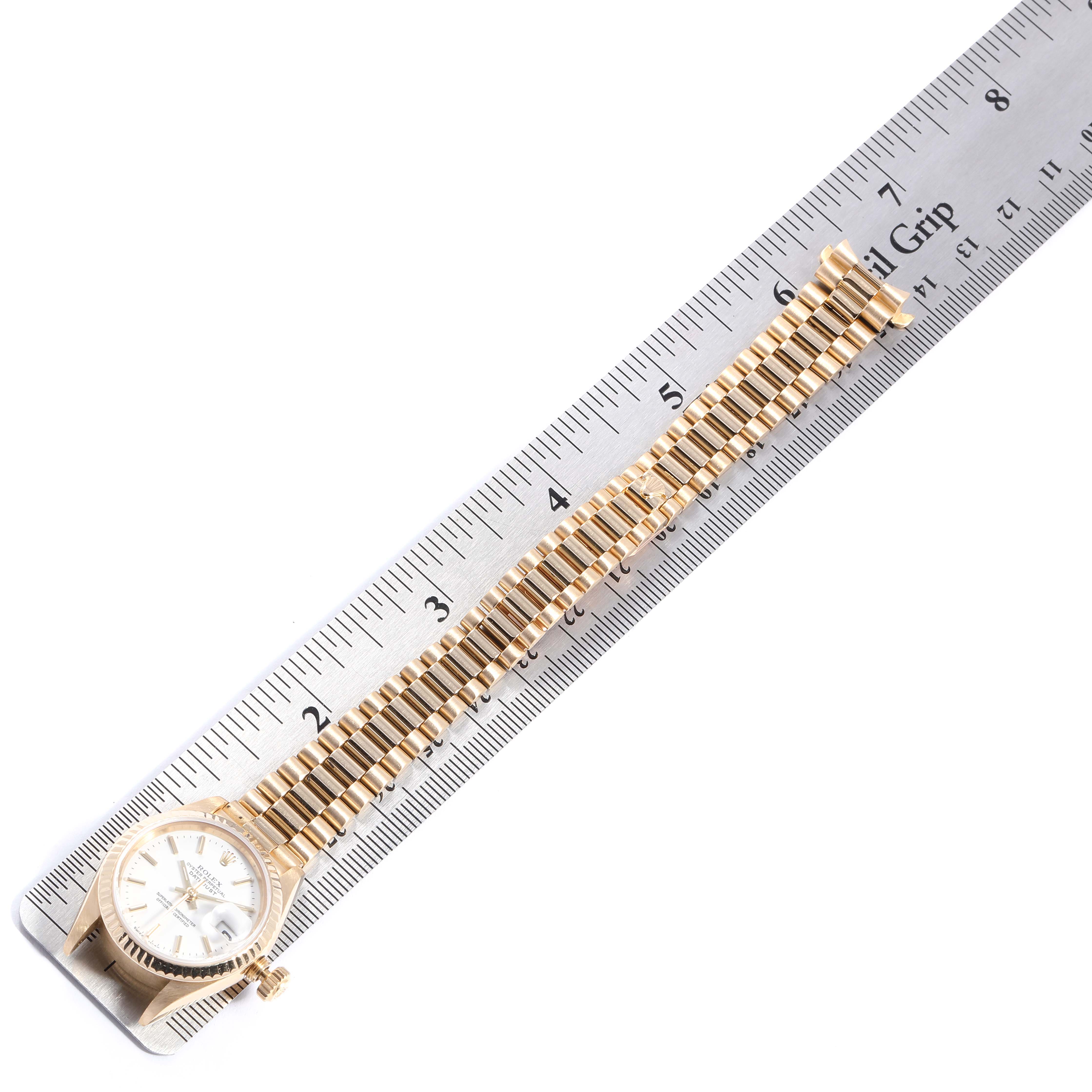 The image shows a side view of a Rolex President 69178 Women
s Yellow Gold White Dial 69178 Women
s Yellow Gold White Dial model watch, highlighting the watch face, bezel, and bracelet alongside a ruler.