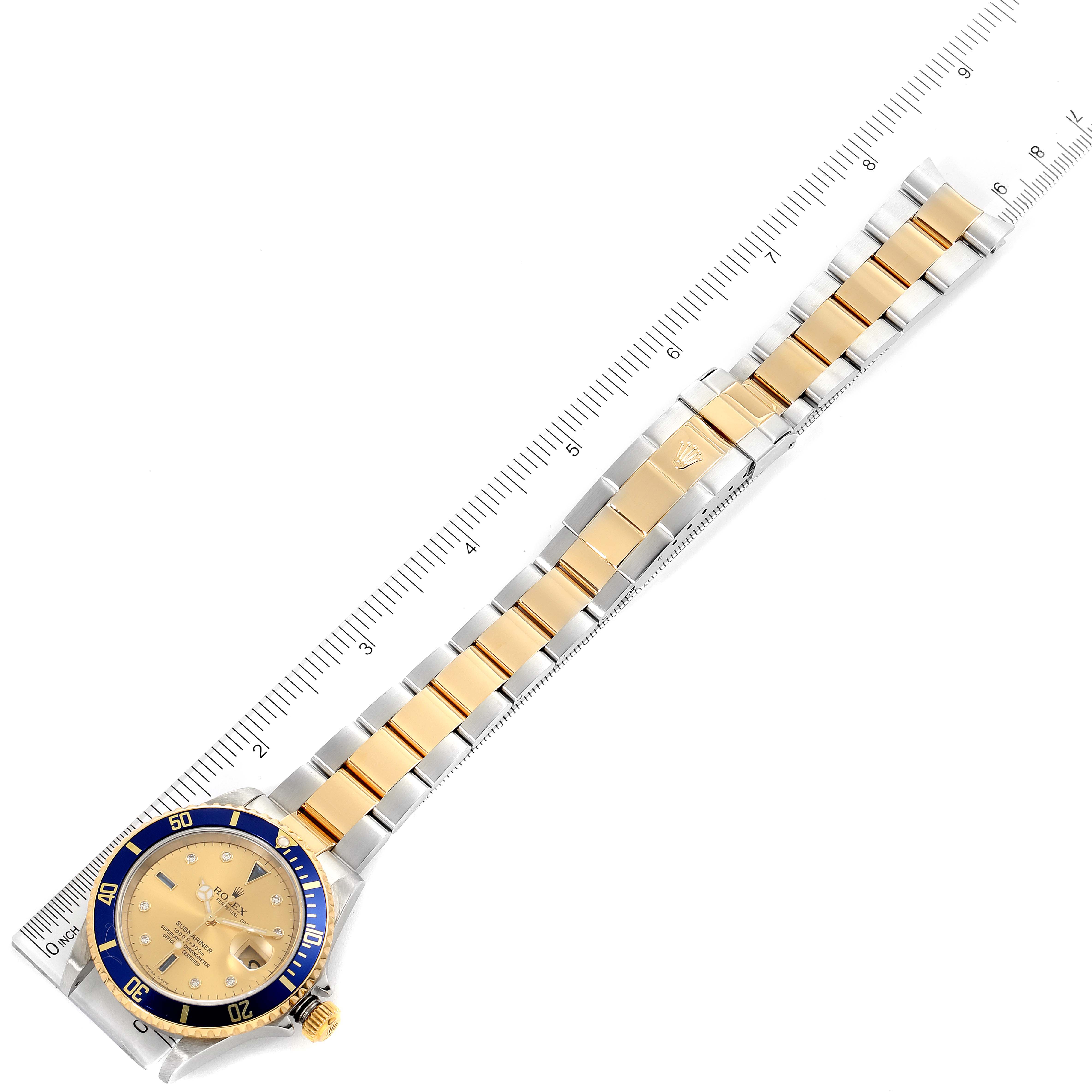This image shows a Rolex Submariner 16613 Men's Steel and Gold (two tone) Champagne Dial 16613 Men's Steel and Gold (two tone) Champagne Dial watch laid flat, highlighting the watch face, bezel, and two-tone bracelet against a ruler backdrop.