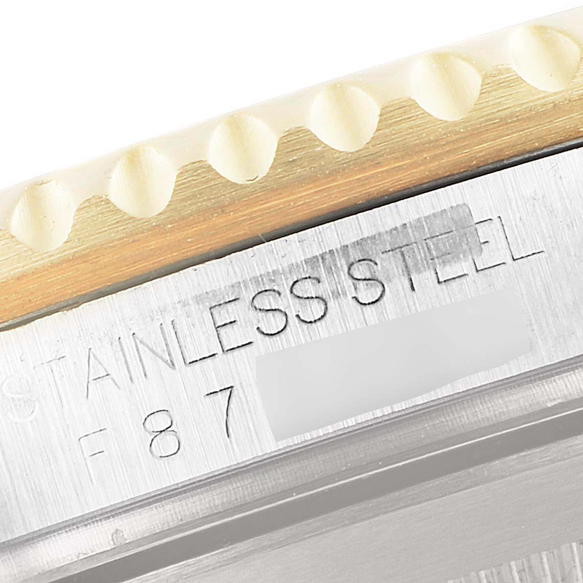 This close-up image shows part of the case and bezel of a Rolex Submariner 16613 Men's Steel and Gold (two tone) Champagne Dial 16613 Men's Steel and Gold (two tone) Champagne Dial, with the text "STAINLESS STEEL" engraved.