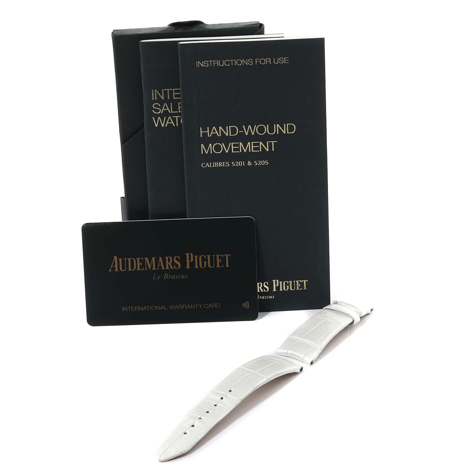 This image shows a white strap, an international warranty card, and instruction booklets for the Audemars Piguet Millenary 77247BC.ZZ.A813CR.01 Women's White Gold Mother of Pearl Dial 77247BC.ZZ.A813CR.01 Women's White Gold Mother of Pearl Dial model.