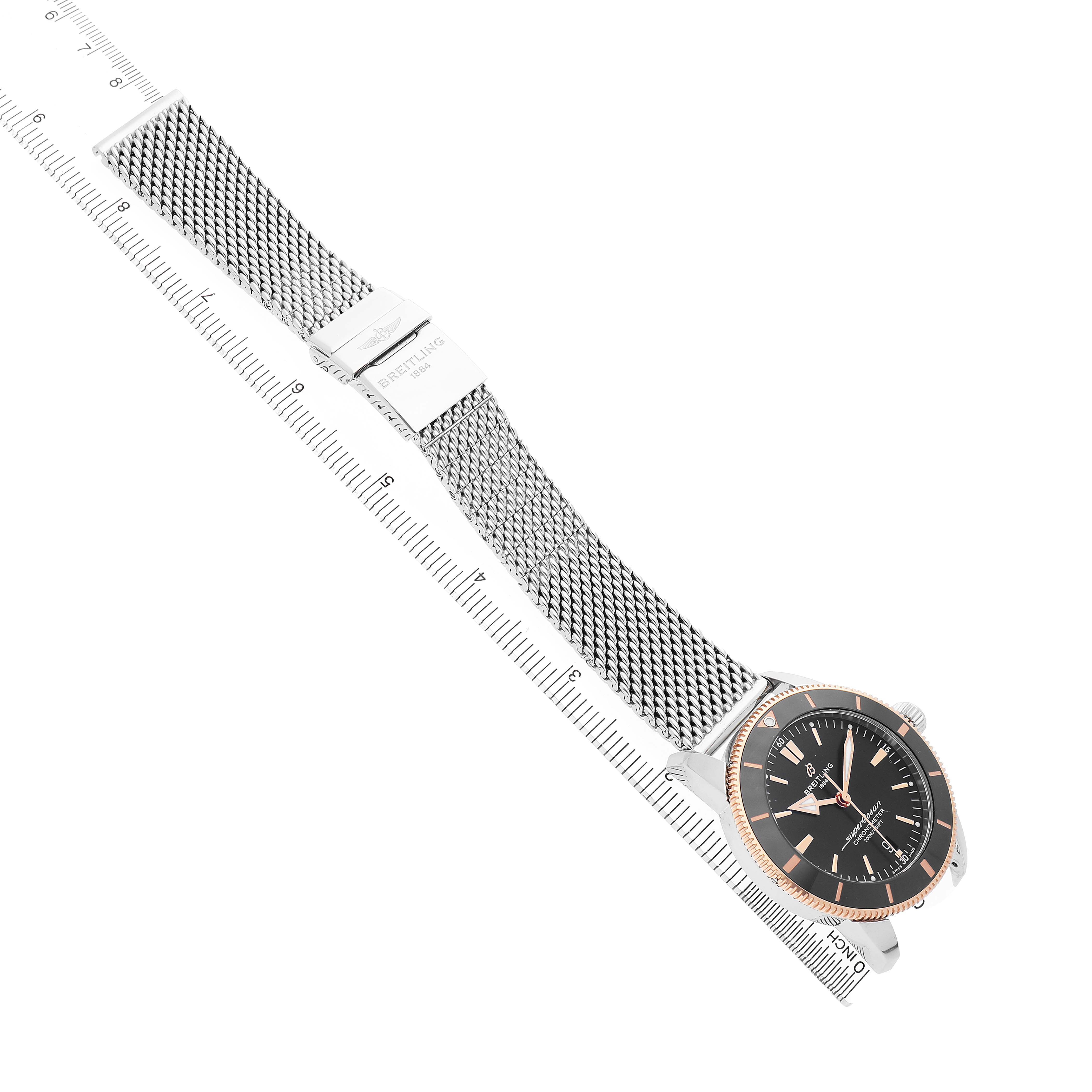 The Breitling Superocean UB2030121B1A1 Men's Stainless Steel Black Dial watch is shown at an angled top view, displaying the mesh bracelet and the watch face prominently.