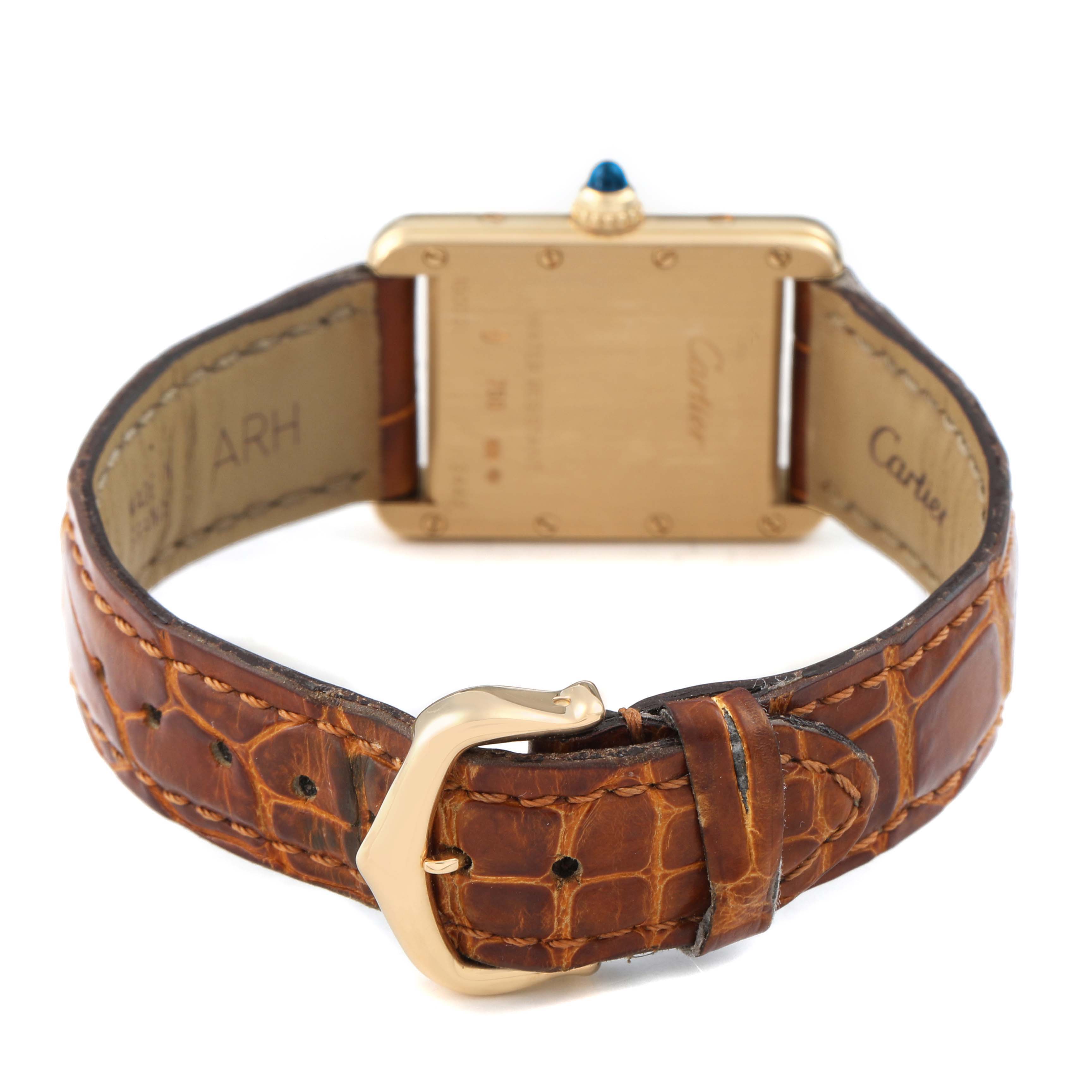 The Cartier Tank Louis W1529856 Women's Yellow Gold Silver Dial watch is shown from the back, highlighting the gold case, leather strap, and buckle.