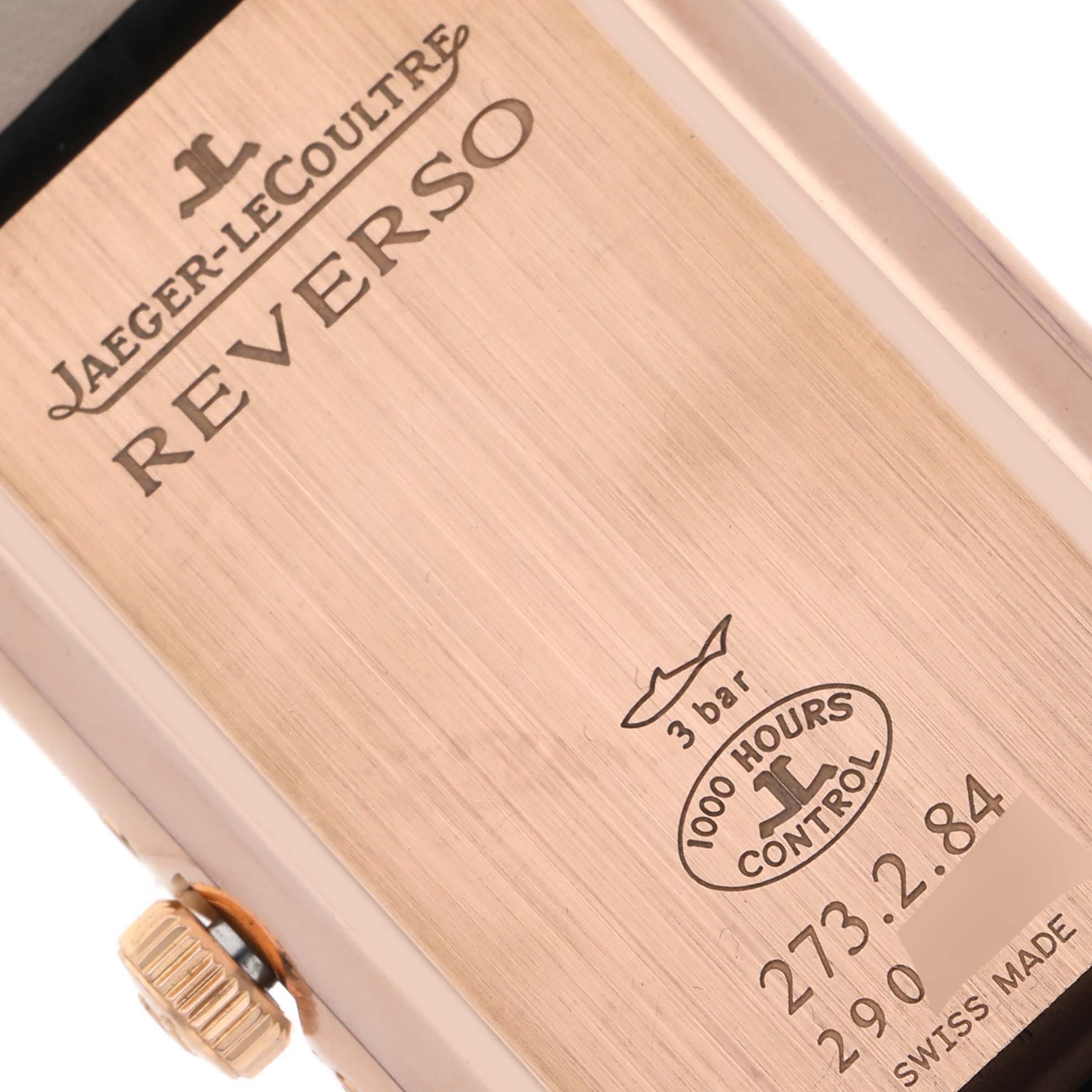 The image shows the back of a Jaeger-LeCoultre Reverso watch, highlighting engravings and the crown.
