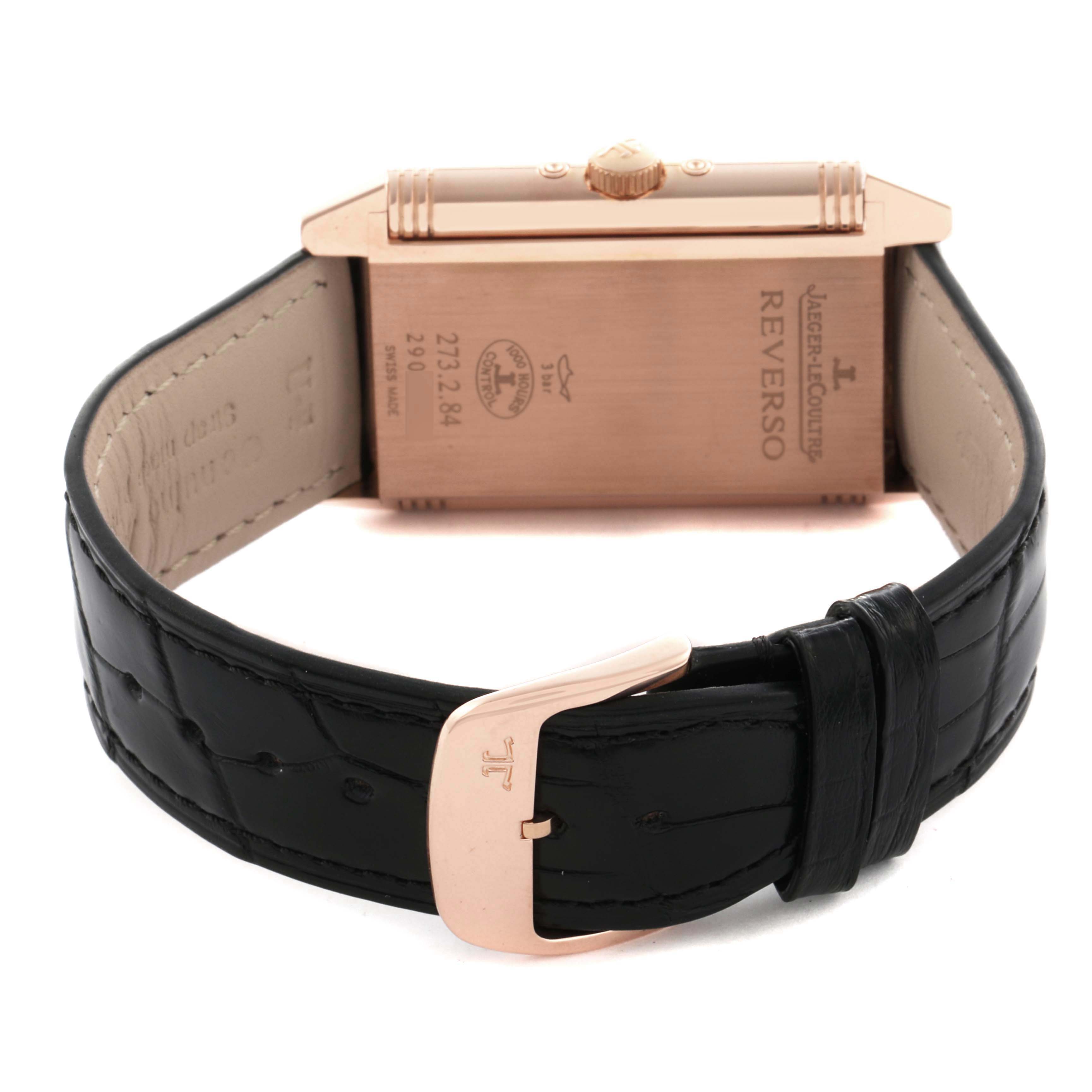 The image shows the back of a Jaeger-LeCoultre Reverso watch, including the case back, crown, and part of the black leather strap.