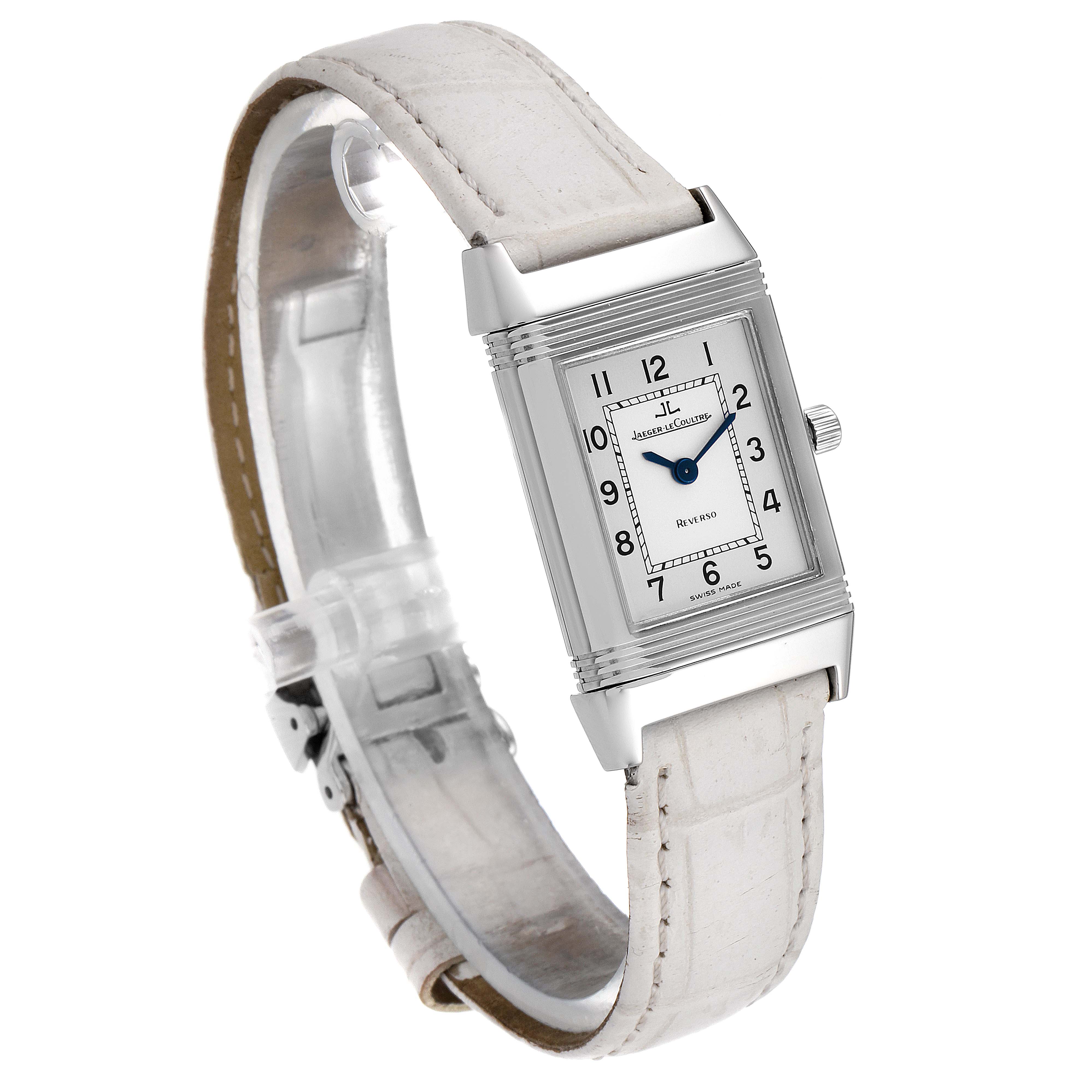 The image shows a Jaeger-LeCoultre Reverso watch at an angle highlighting the dial, case, crown, and white leather strap.