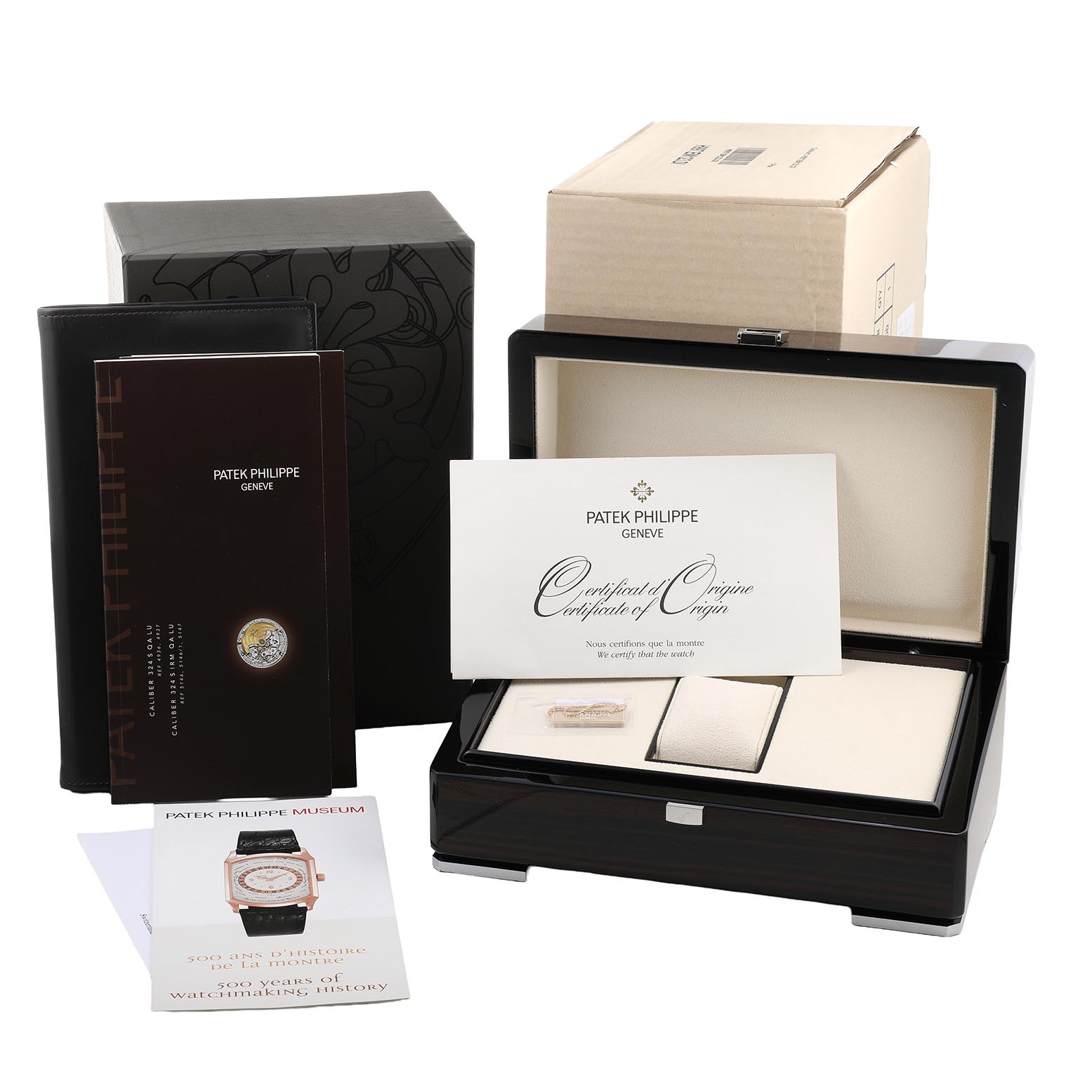 The image shows the Complications model by Patek Philippe from an angled perspective, including its box, certificate, and documents.
