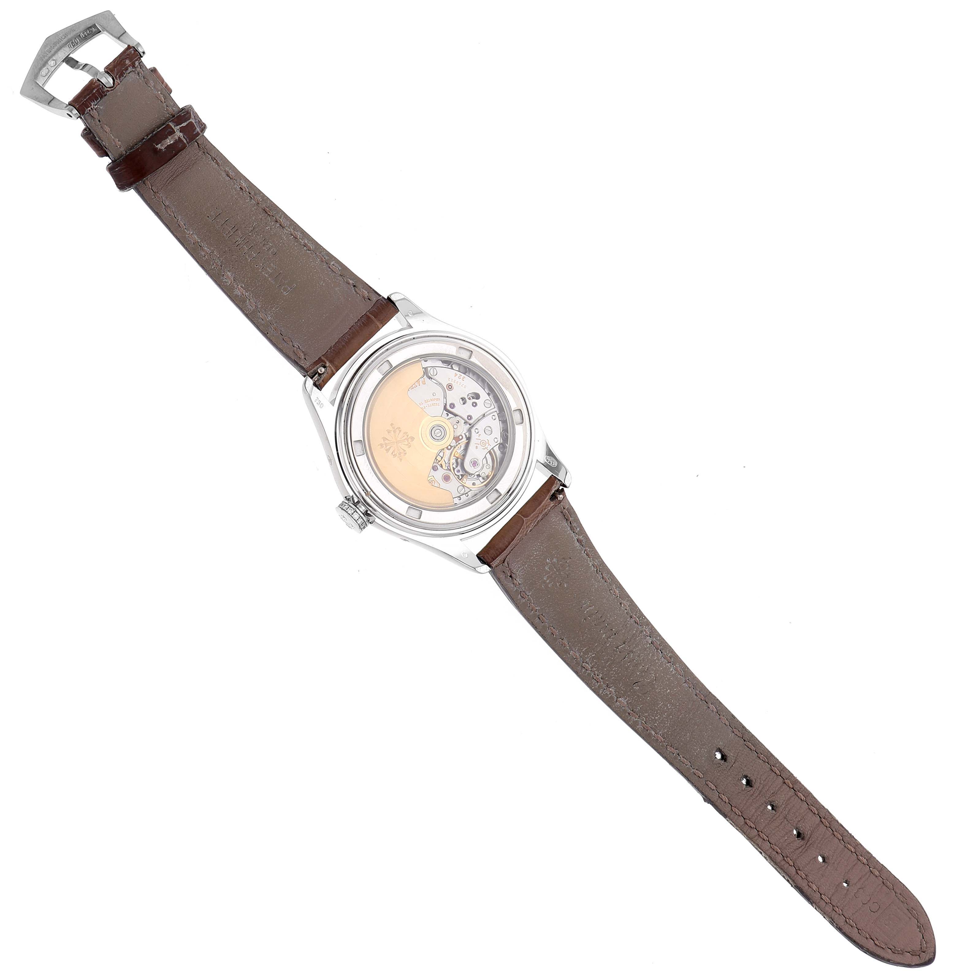 The image shows a Patek Philippe Complications 4936G - 001 Men's White Gold Mother of Pearl Dial watch from the back, revealing its intricate movement and leather strap.