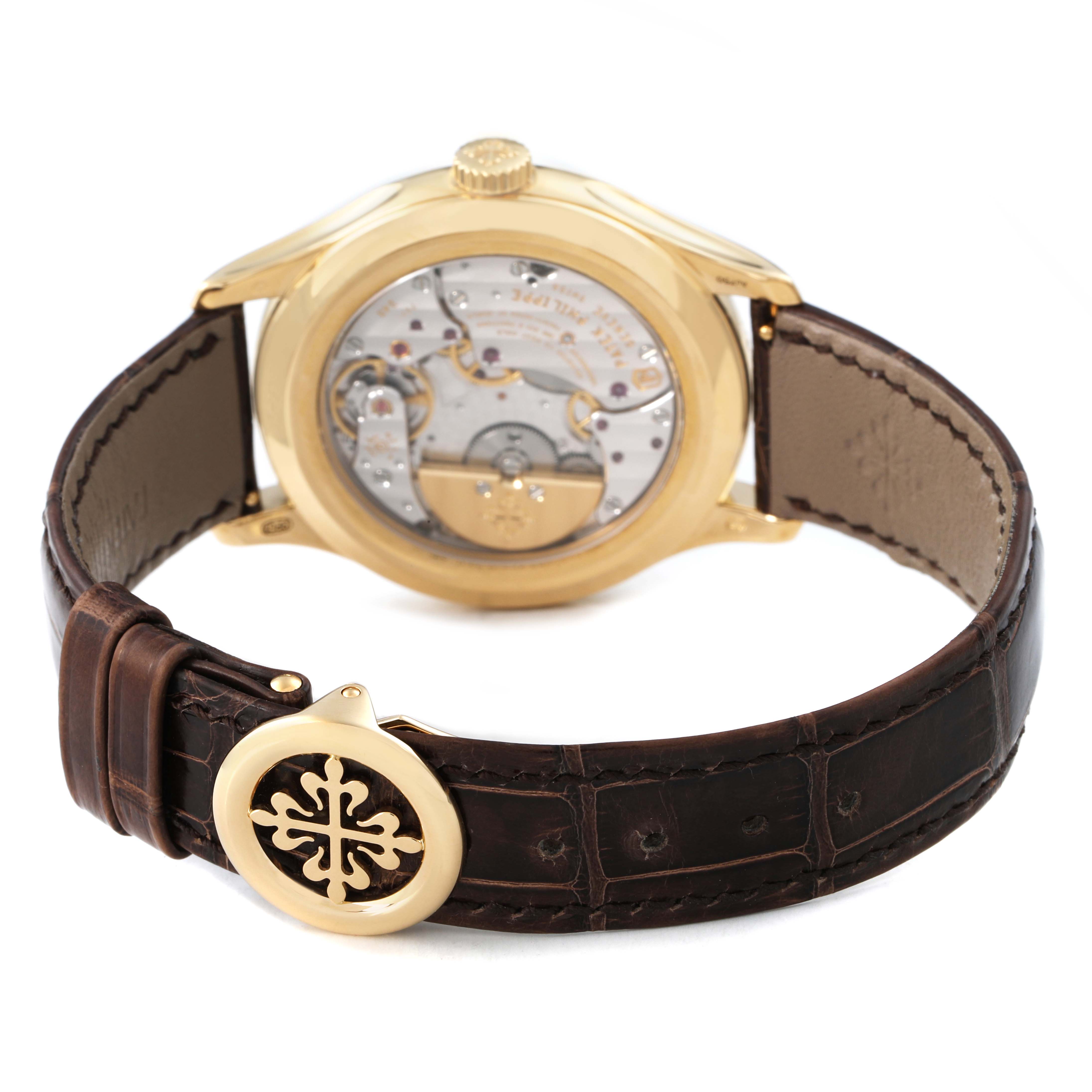 The image shows the back view of the Patek Philippe Complications 5327J-001 Men's Yellow Gold Beige Dial model, highlighting the movement and leather strap.