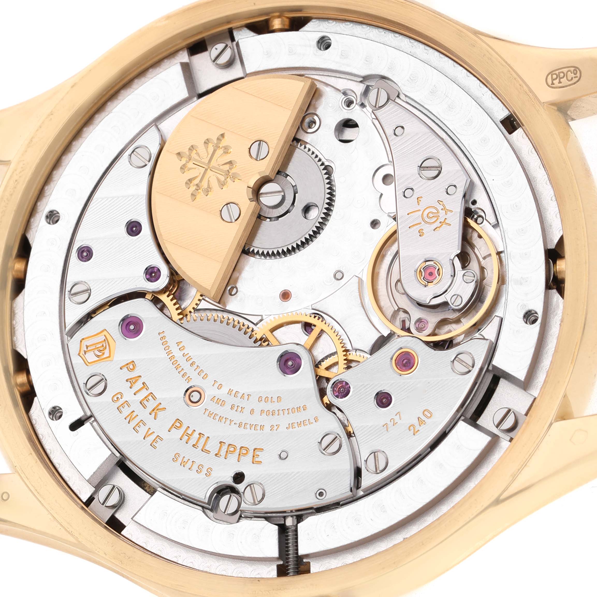 The image shows the Patek Philippe Complications 5327J-001 Men's Yellow Gold Beige Dial model's movement from the back, highlighting gears and inscriptions.