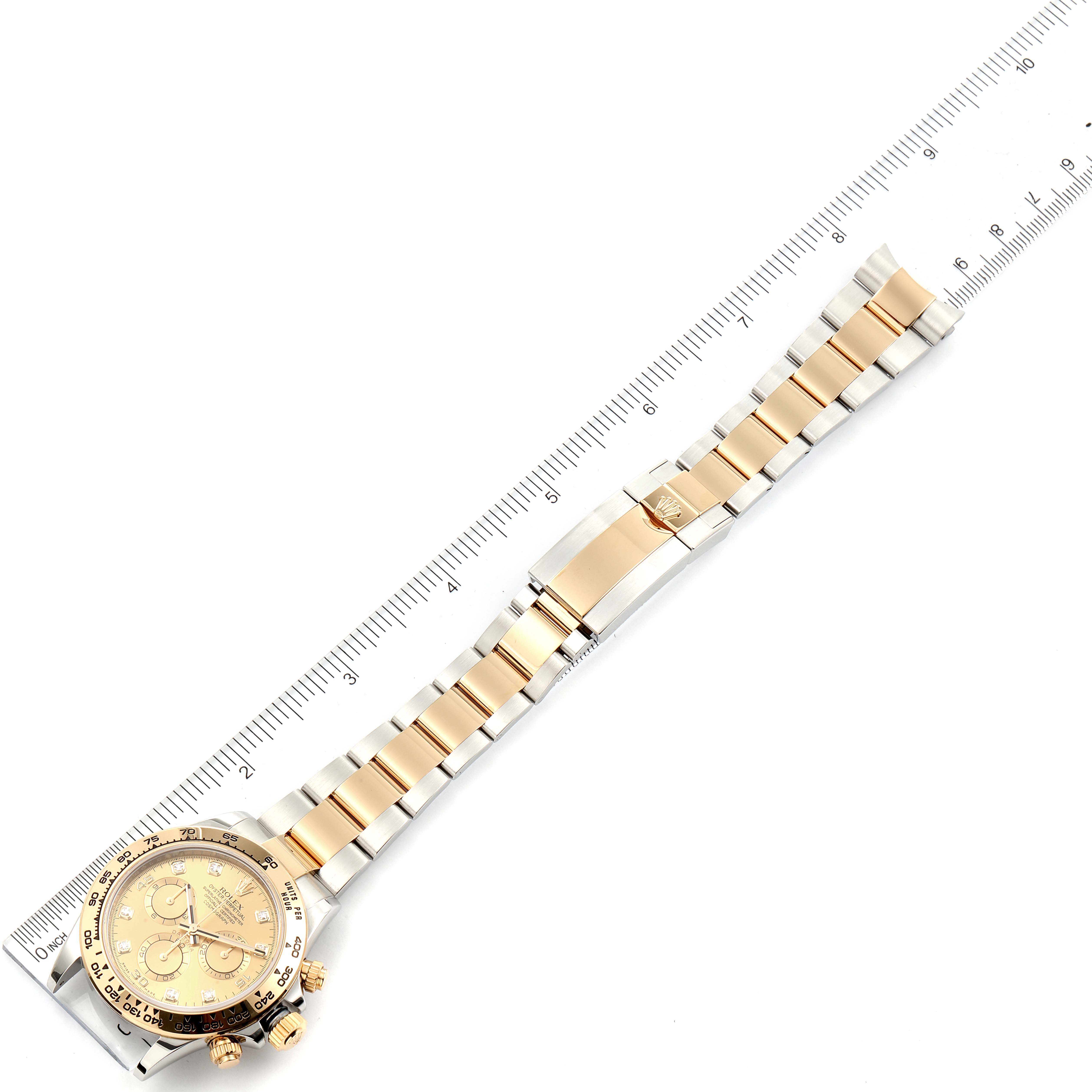 The image shows a Rolex Daytona 116503 Men's Steel and Gold (two tone) Champagne Dial 116503 Men's Steel and Gold (two tone) Champagne Dial watch laid flat, with a focus on its bracelet and face, positioned alongside a ruler.