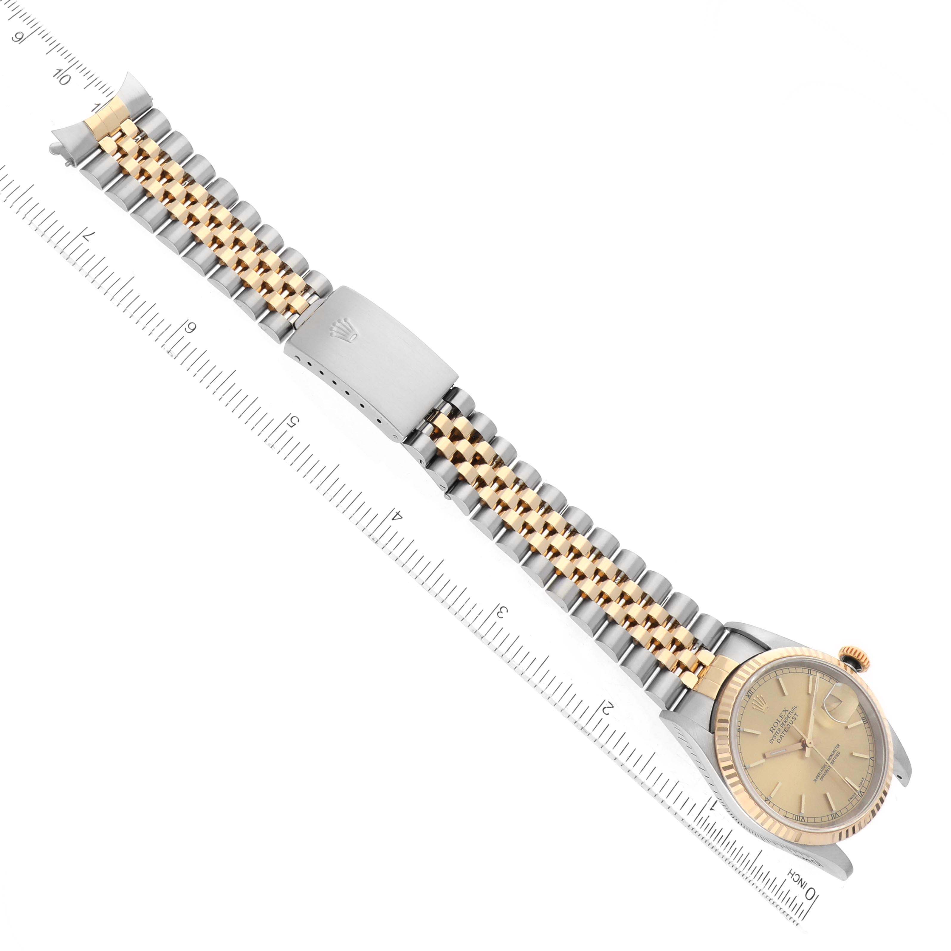 The image shows a Rolex Datejust 16233 Men's Steel and Gold (two tone) Champagne Dial 16233 Men's Steel and Gold (two tone) Champagne Dial watch at a top-down angle, displaying the face and entire two-tone bracelet with a ruler beside it.