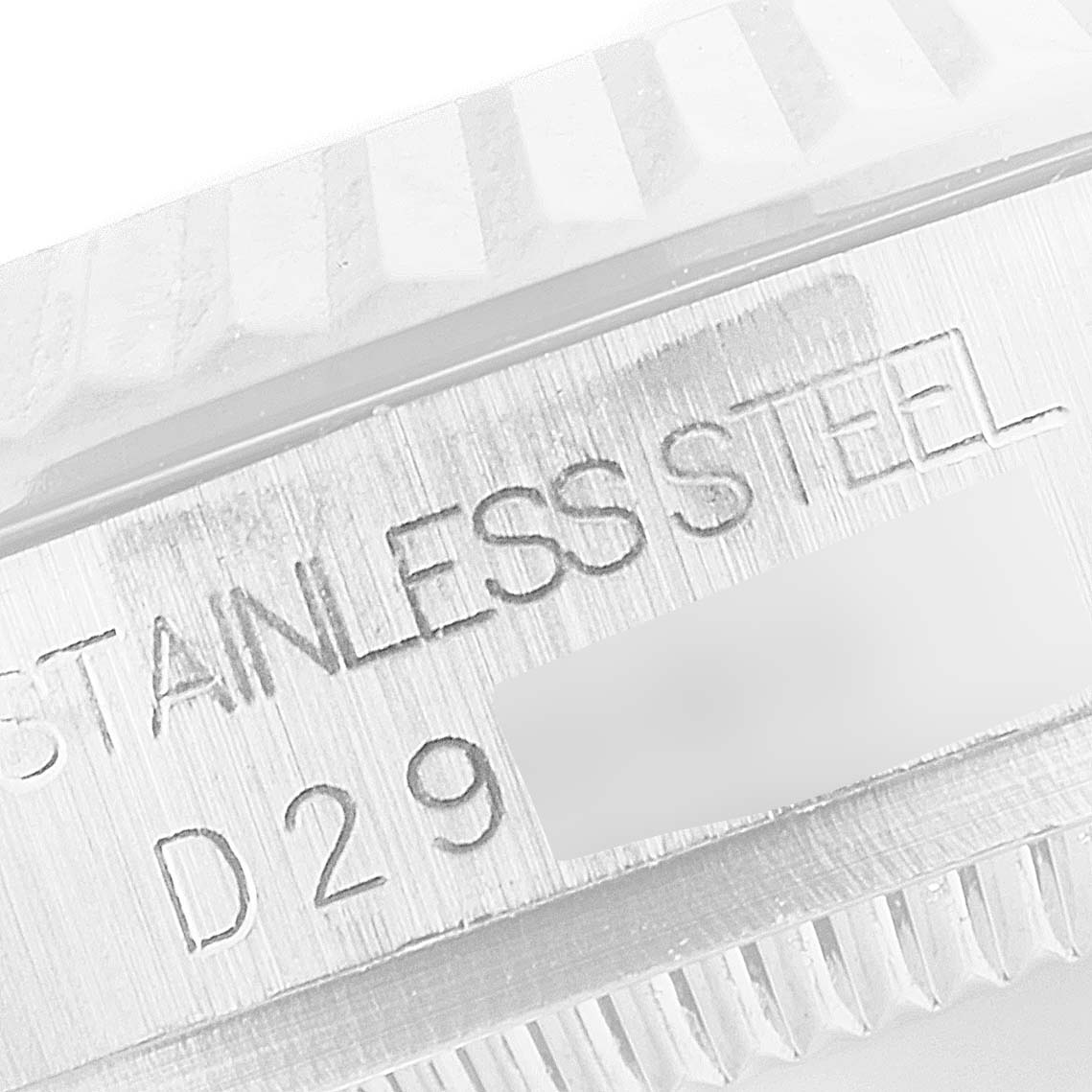The image shows a close-up of the case side of a mid-size Rolex watch, highlighting the engraved "STAINLESS STEEL" inscription.