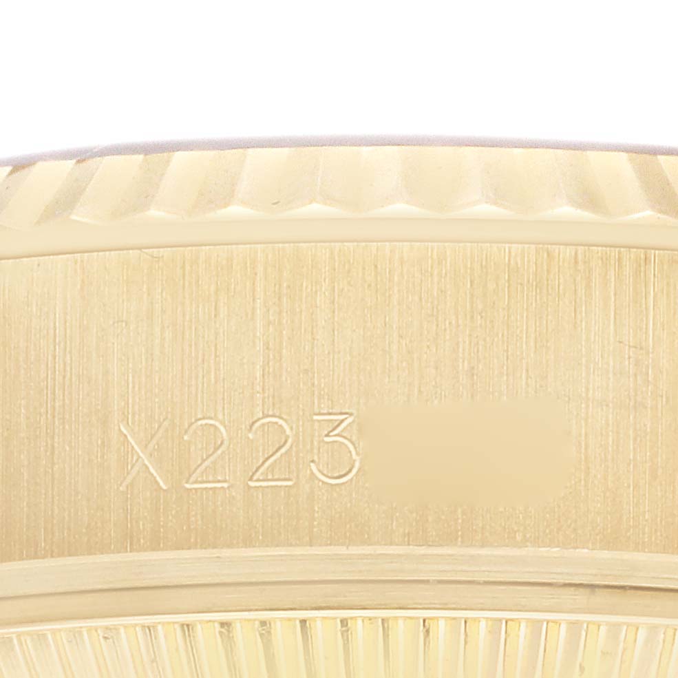 The image shows a close-up of the case side of a Rolex President 69178 Women
s Yellow Gold Champagne Dial 69178 Women
s Yellow Gold Champagne Dial model watch, focusing on the fluted bezel and engraved serial number.