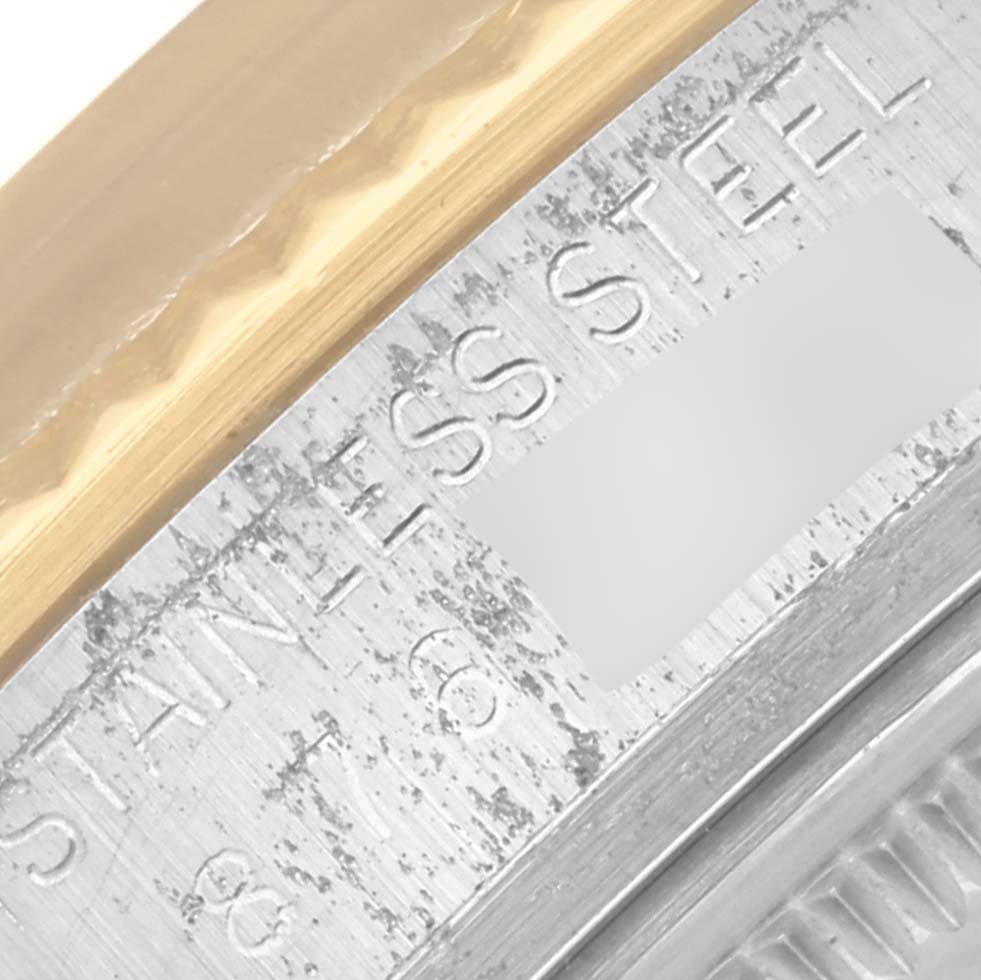 This close-up image shows the edge of a Rolex Datejust 16013 Men's Steel and Gold (two tone) Champagne Dial 16013 Men's Steel and Gold (two tone) Champagne Dial watch, featuring part of the bezel and the engraved "Stainless Steel" text on the case.
