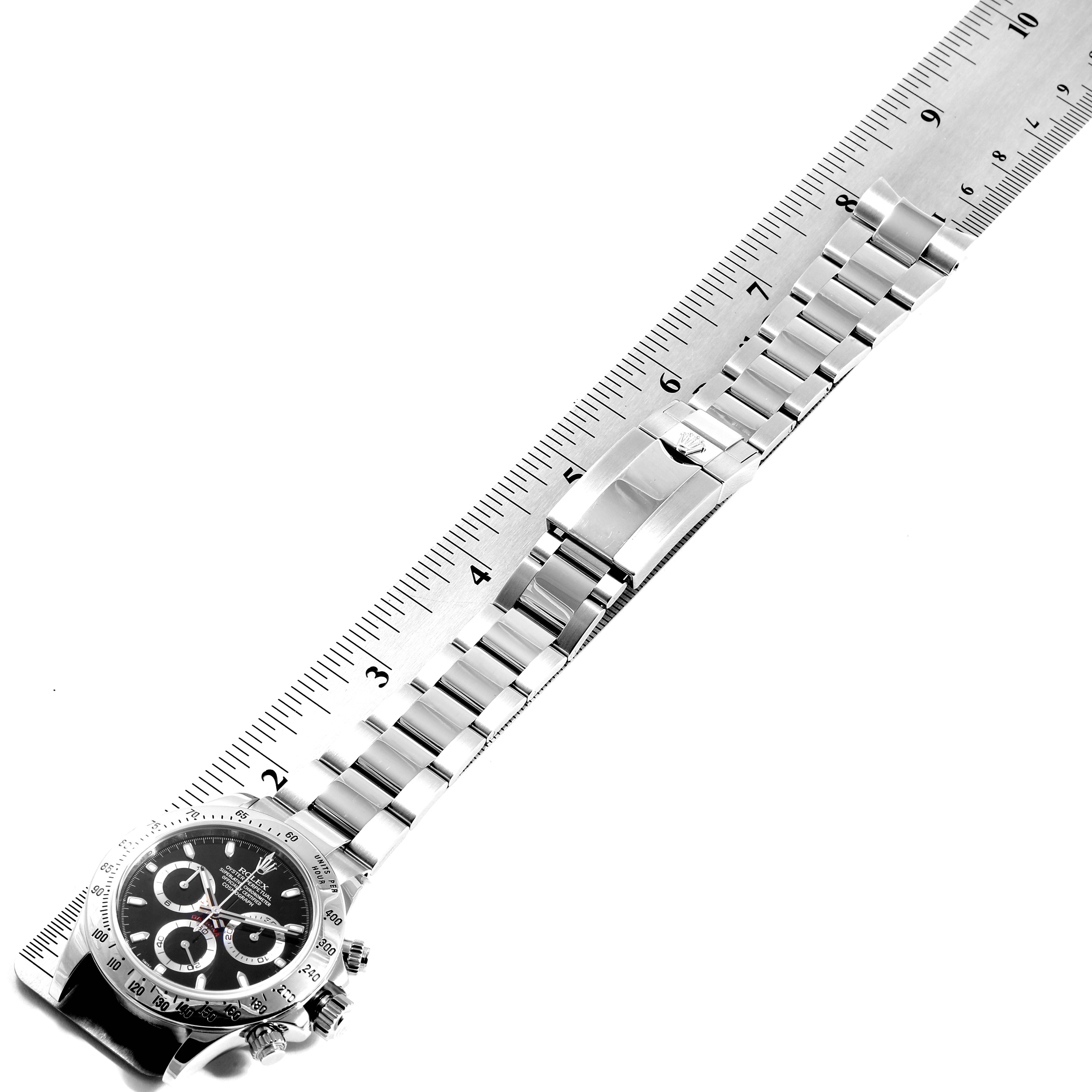 The image shows a top-down view of a Rolex Daytona 116520 Men's Stainless Steel Black Dial 116520 Men's Stainless Steel Black Dial watch with its bracelet extended next to a ruler.