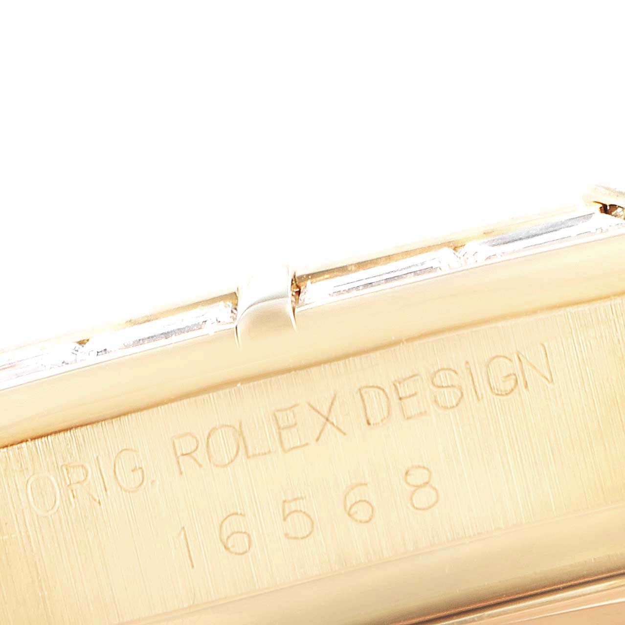This close-up image shows the engraved model number and "ORIG. ROLEX DESIGN" inscription on a Rolex Daytona 16568 Men's Yellow Gold Black Dial 16568 Men's Yellow Gold Black Dial watch.