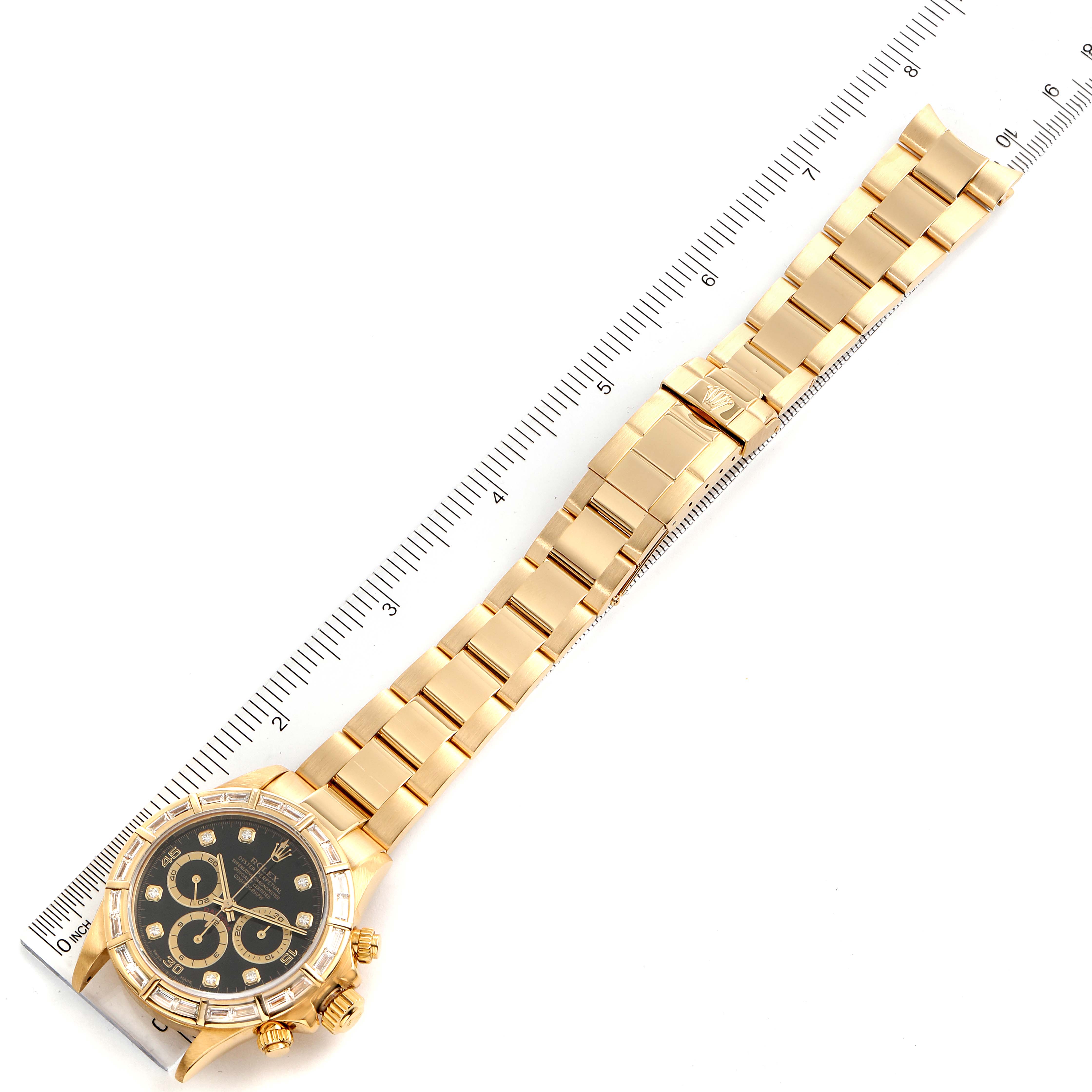 The image shows a full view of the Rolex Daytona 16568 Men's Yellow Gold Black Dial 16568 Men's Yellow Gold Black Dial watch, laid flat with a ruler measuring its length.