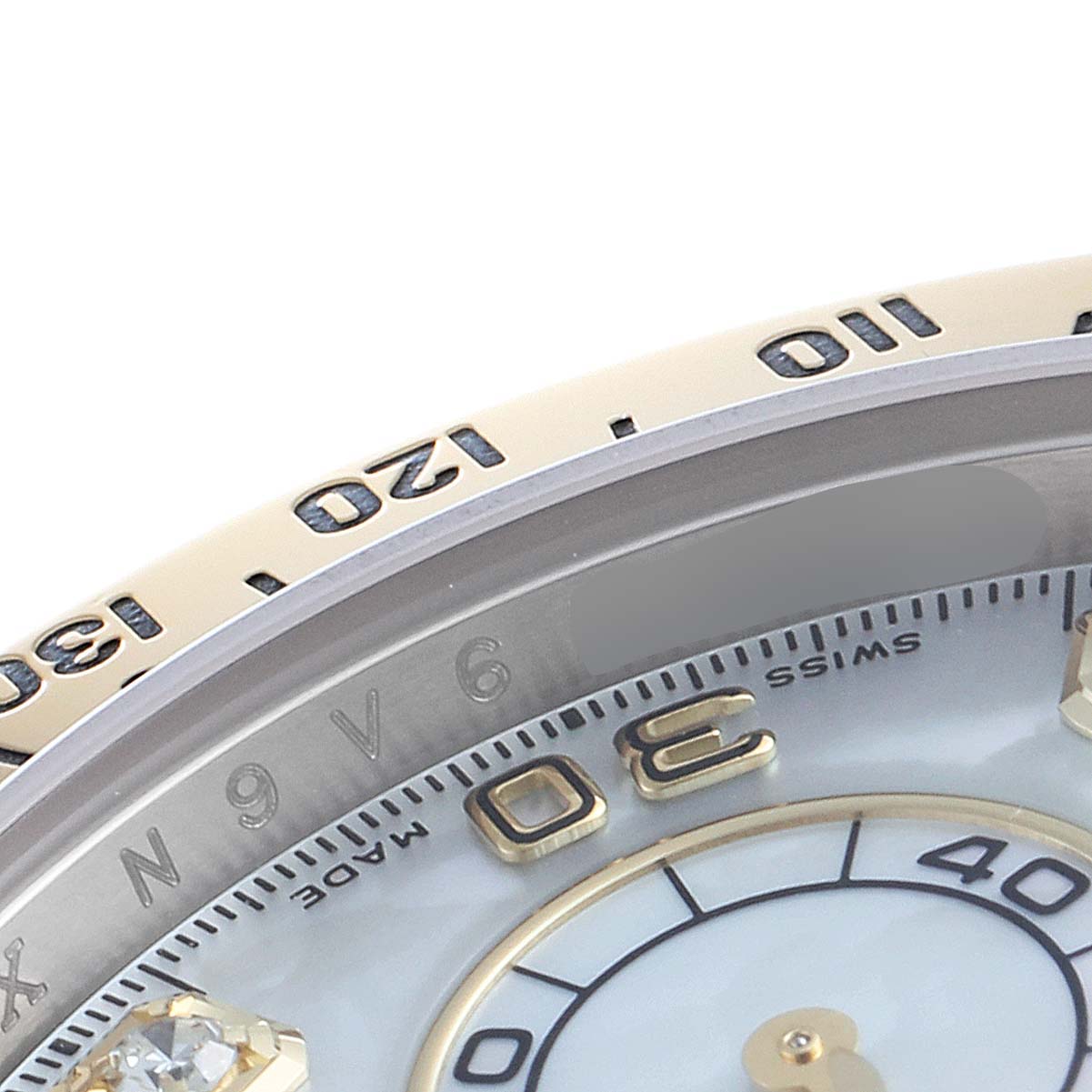The image shows a close-up of the bezel and part of the dial of a Rolex Daytona 116523 Men's Steel and Gold (two tone) Mother of Pearl Dial 116523 Men's Steel and Gold (two tone) Mother of Pearl Dial watch.