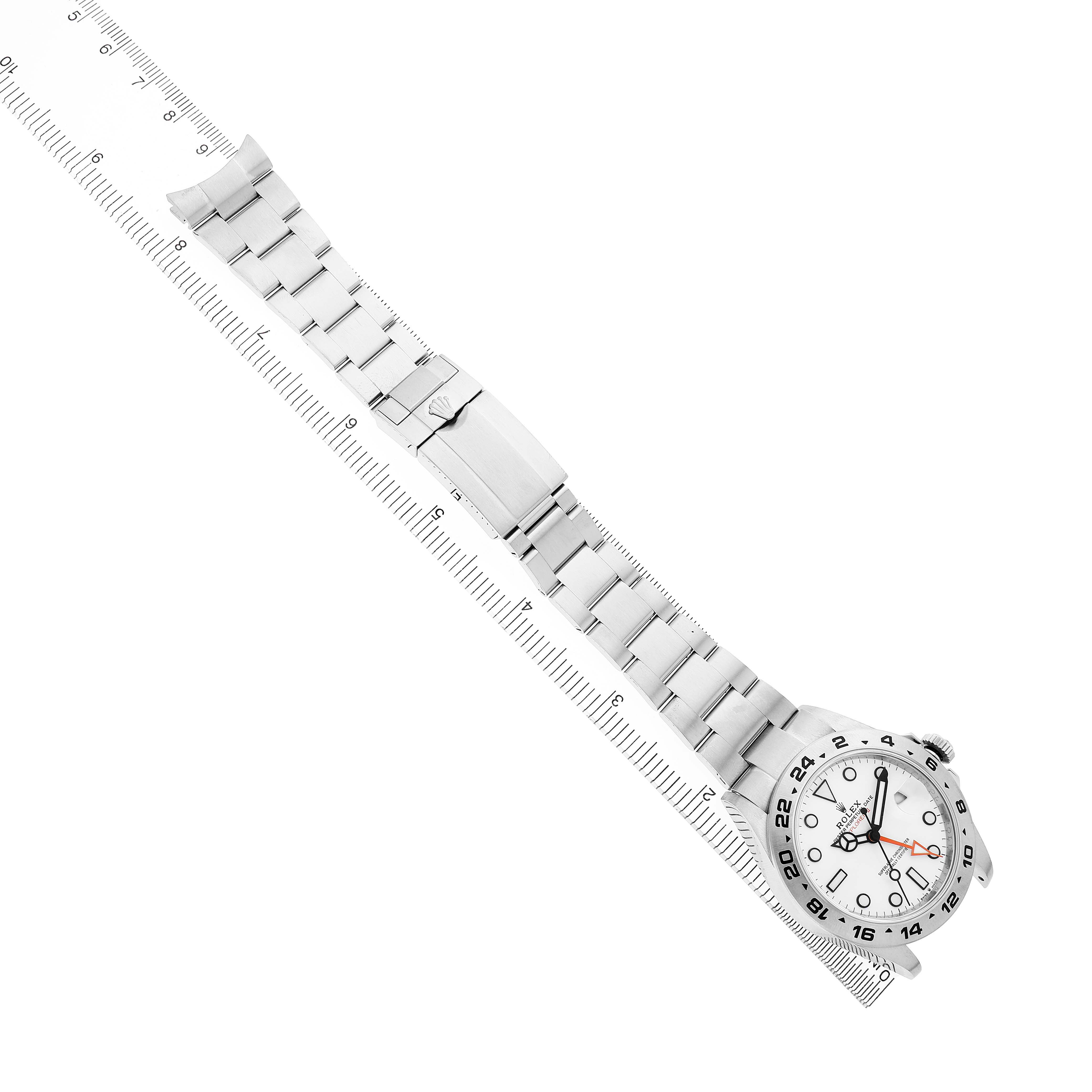 The Rolex Explorer M226570-001 Men's Stainless Steel White Dial watch is shown from a top view, featuring the face, metal bracelet, and clasp with a ruler underneath.