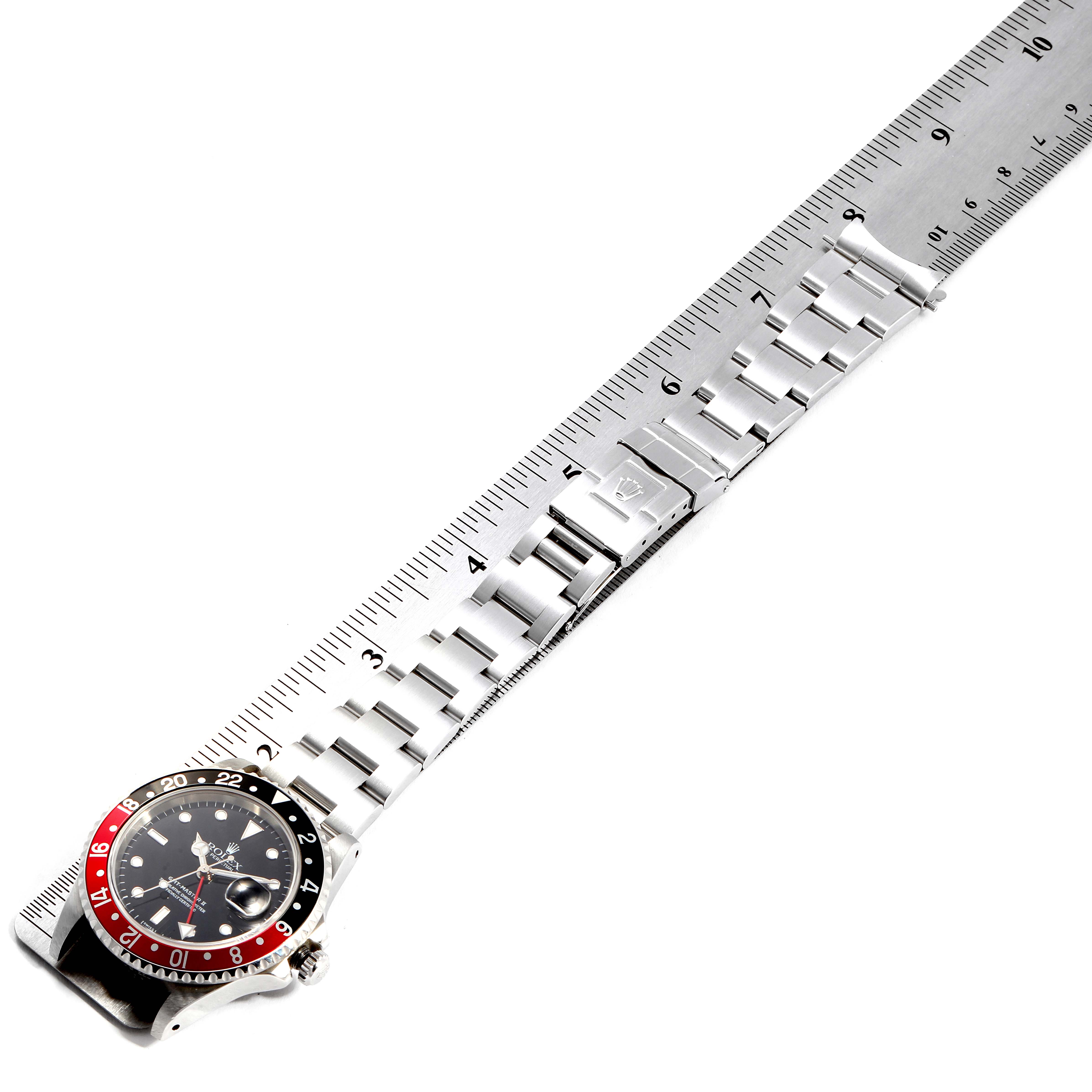 The image shows a top-down view of a Rolex GMT-Master 16710 Men
s Stainless Steel Black Dial 16710 Men
s Stainless Steel Black Dial watch, highlighting its face, bezel, and metal bracelet next to a ruler.