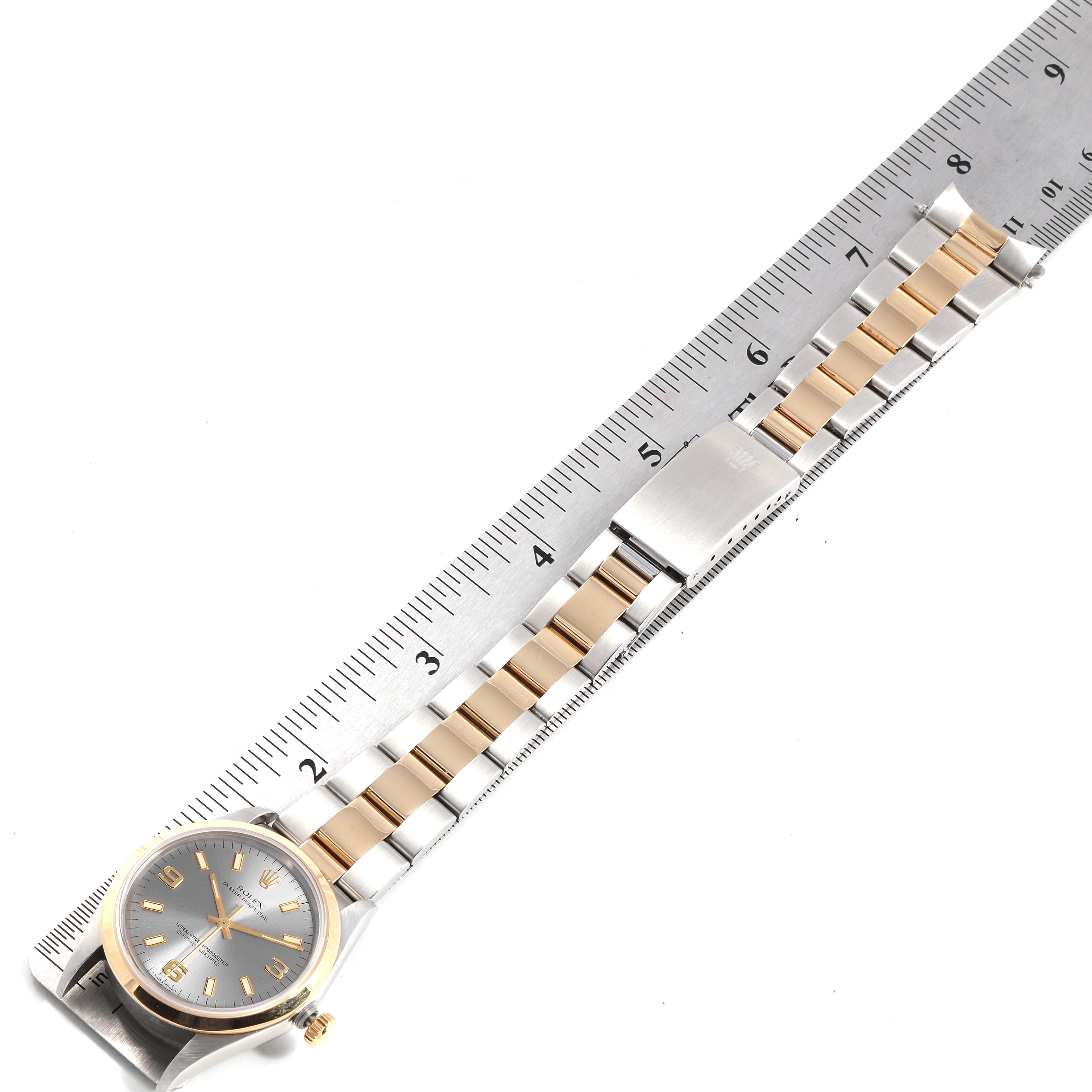 The image shows a Rolex Oyster Perpetual 14203 Men's Steel and Gold (two tone) Grey Dial 14203 Men's Steel and Gold (two tone) Grey Dial watch lying flat against a ruler, highlighting the watch face, bracelet, and clasp.