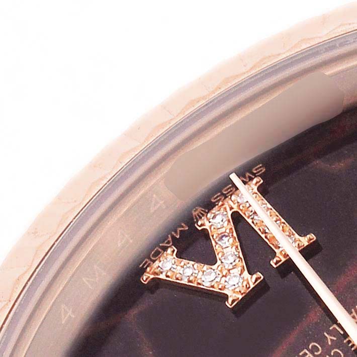 The image shows a close-up of the Rolex President 128235 Men's Rose Gold Brown Dial's watch face, showcasing jeweled Roman numerals and a portion of the minute hand.
