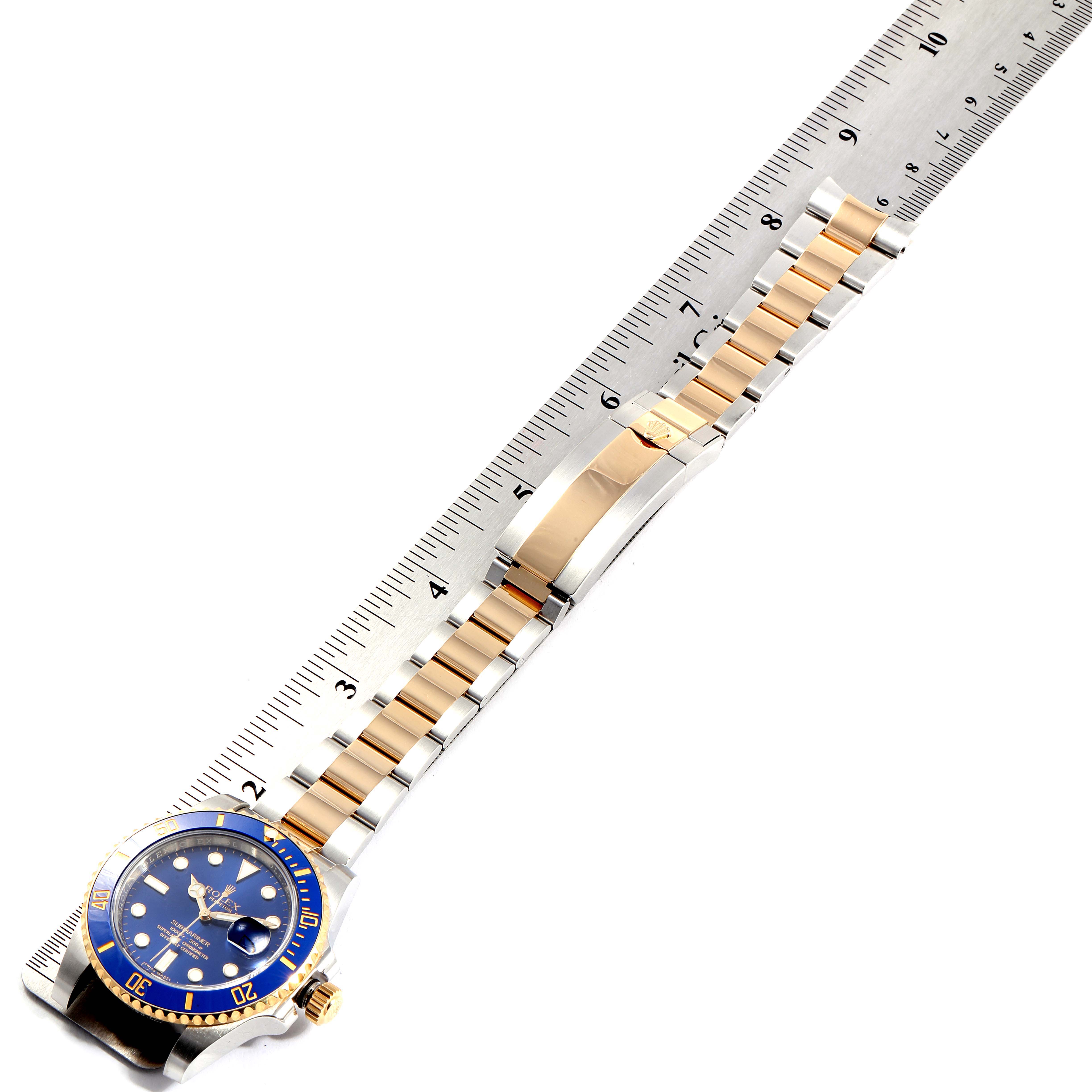 The Rolex Submariner 116613 Men
s Stainless Steel Blue Dial 116613 Men
s Stainless Steel Blue Dial watch is shown from an overhead angle, highlighting the band next to a ruler for measurement.