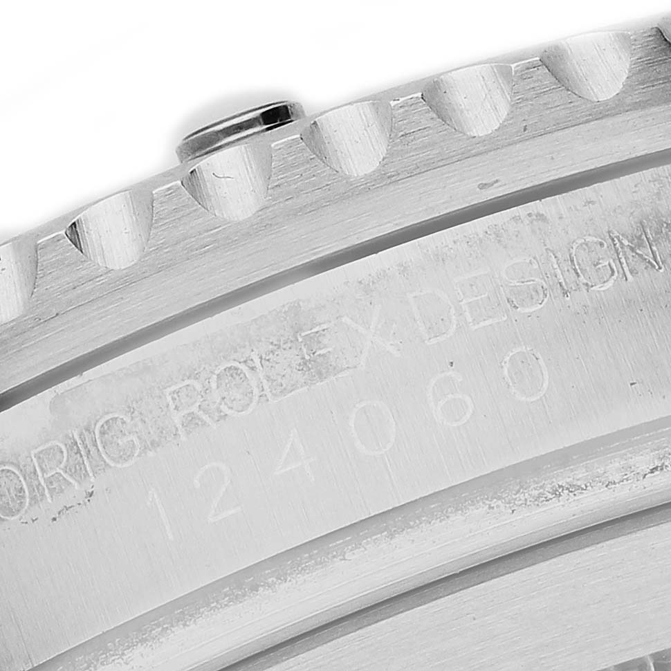The image shows a close-up of the bezel and case edge of a Rolex Submariner M124060-0001 Men's Stainless Steel Black Dial, with visible engravings and watch teeth.