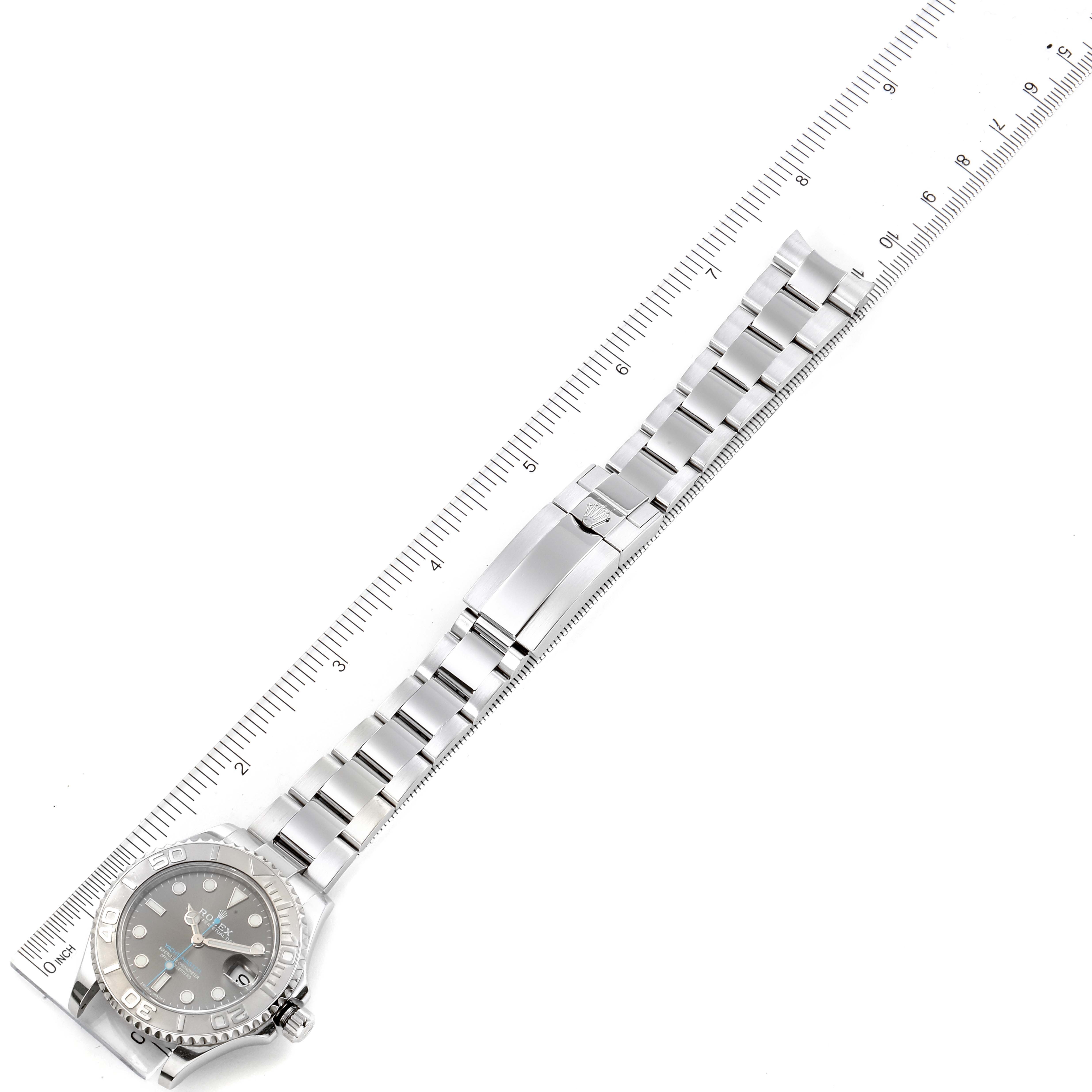 The Yacht-Master Rolex watch is shown from a top-down angle, highlighting its face, bracelet, and clasp alongside a ruler.